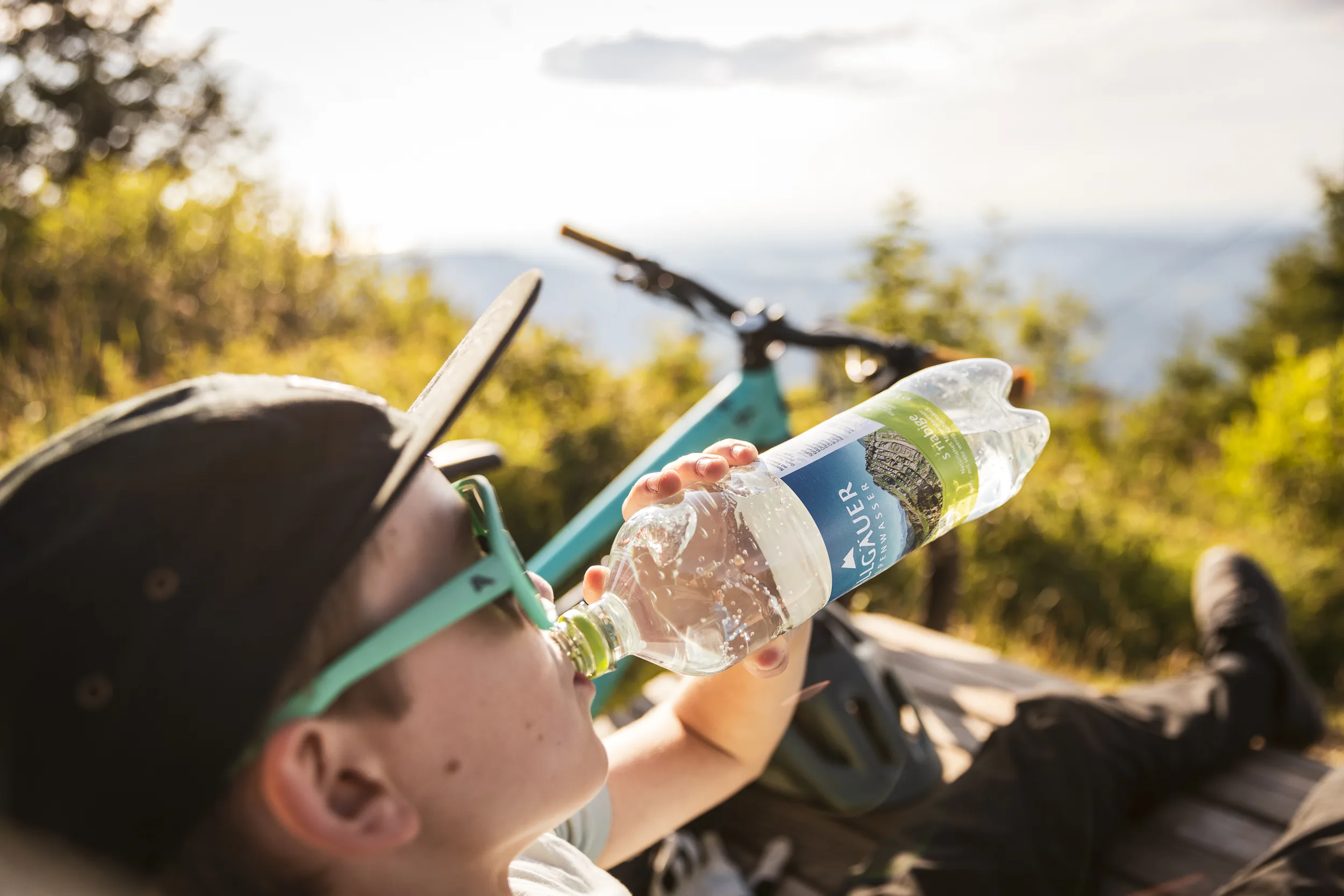 Mountainbiker trinkt bei einer Pause am Bergtrail aus einer Wasserflasche