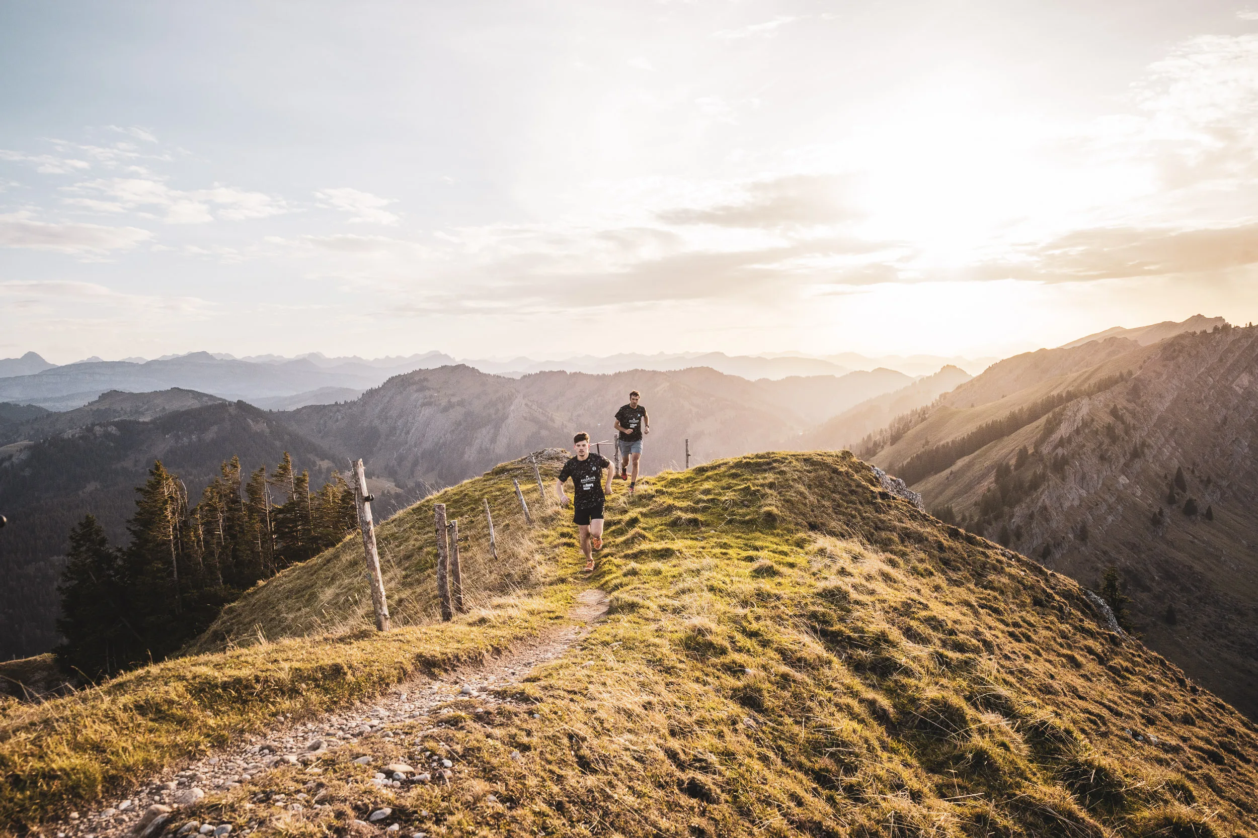 Drei Trailrunner auf einem Bergpfad zwischen Weidezaun und Grat