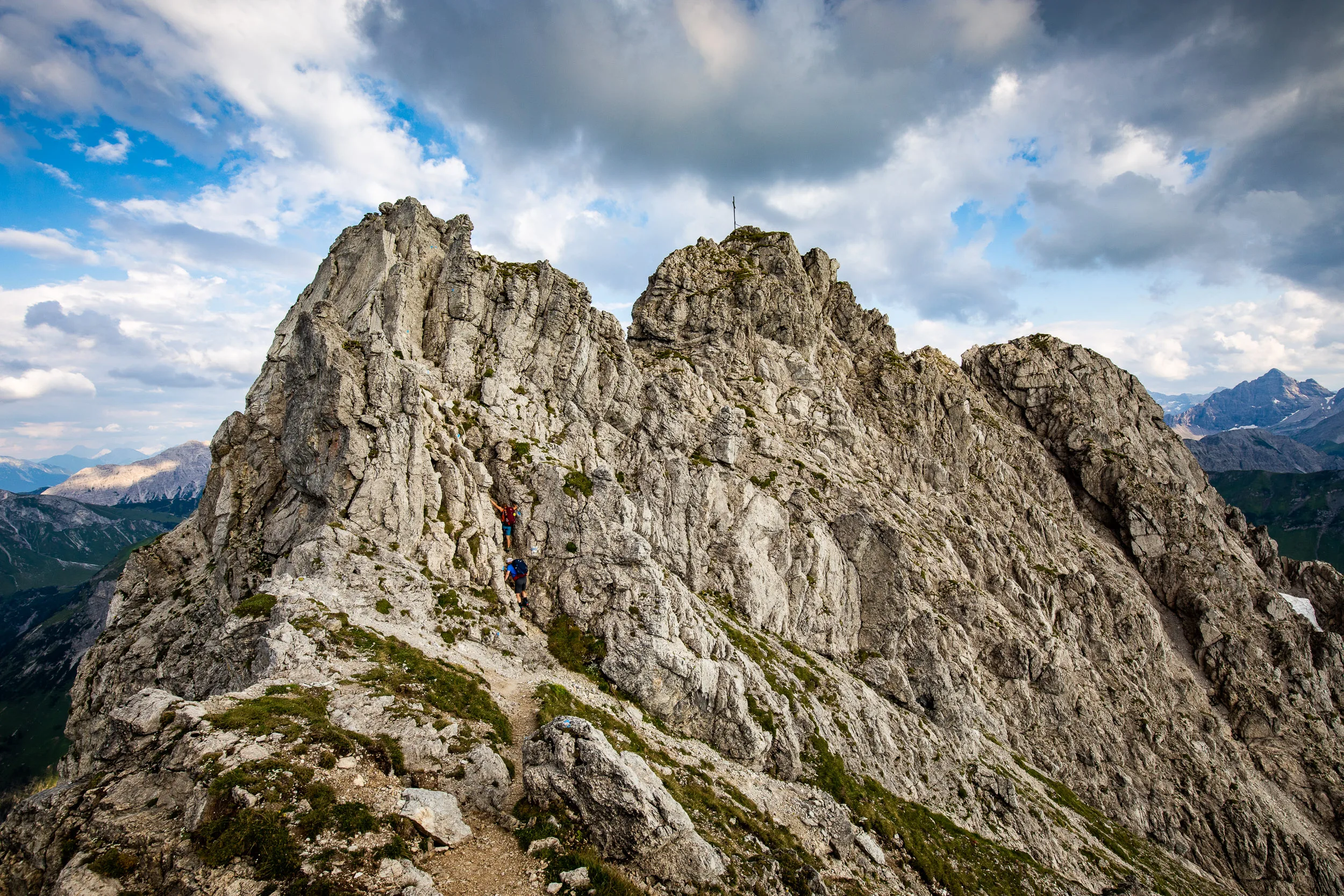 Caroline Nantke und Harald Dreyer bewegen sich über einen felsigen Grat vor weiter Berglandschaft
