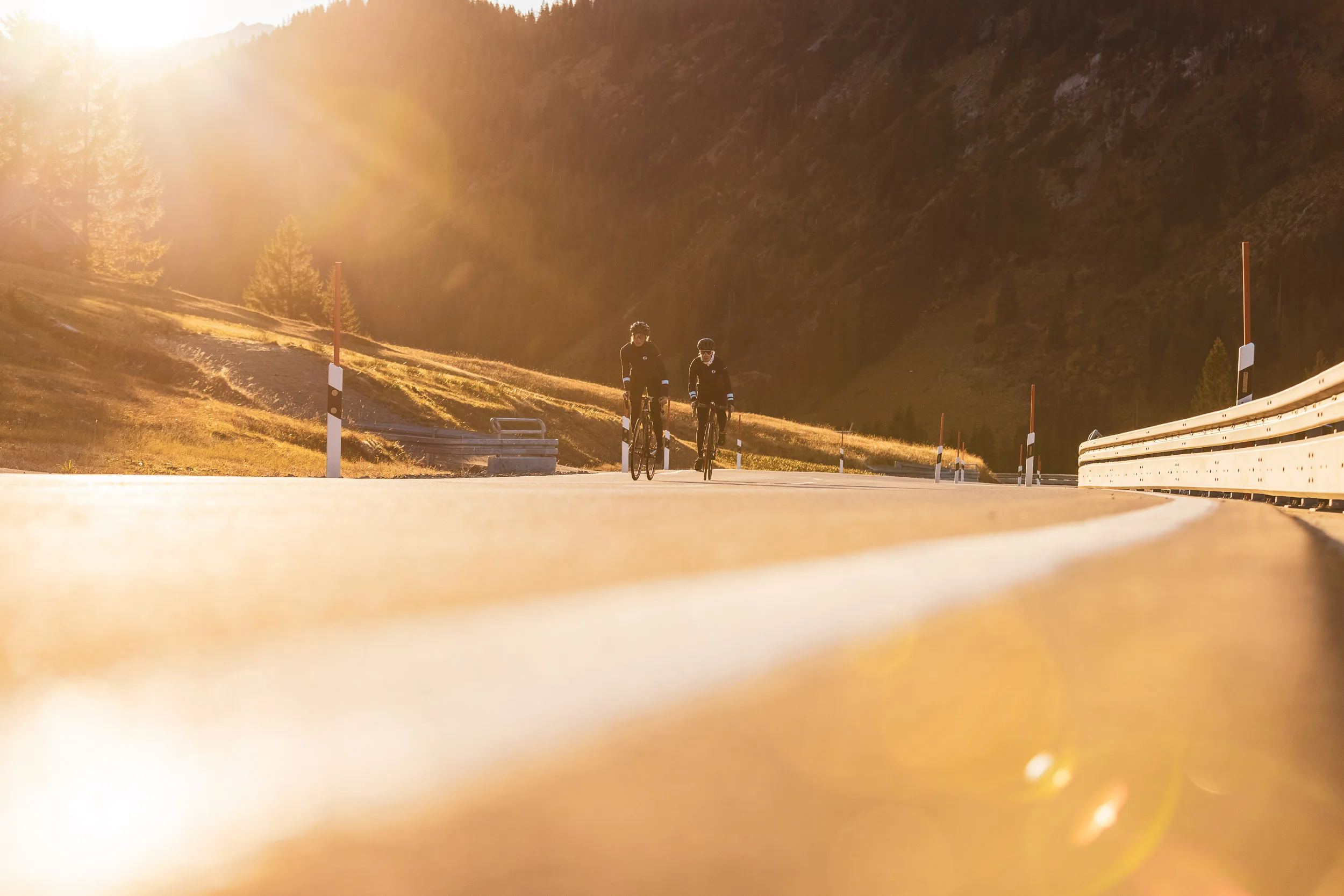 Rennradfahrerin fährt im warmen Gegenlicht über den Riedbergpass