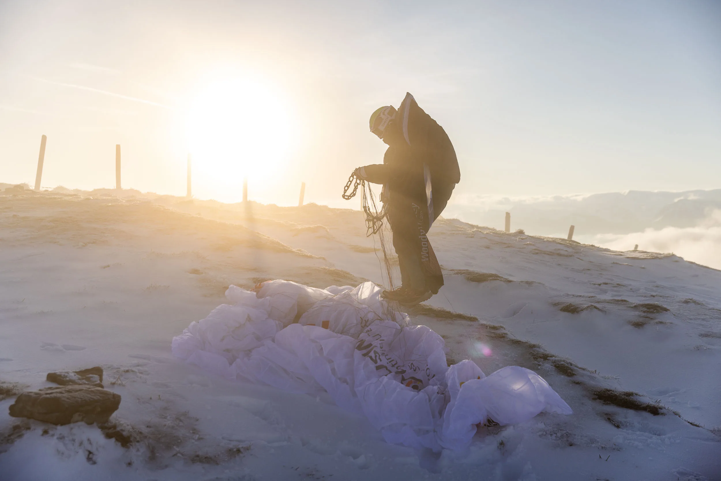 Eli Egger sortiert Leinen neben ihrem Gleitschirm im Schnee.