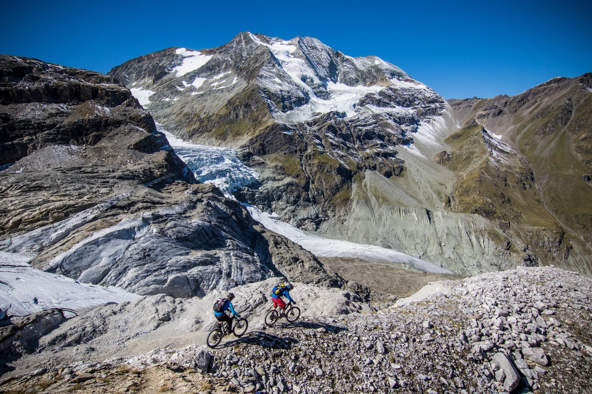 Robert Härle und Florian Häusler queren mit Mountainbikes eine hochalpine Bergflanke.