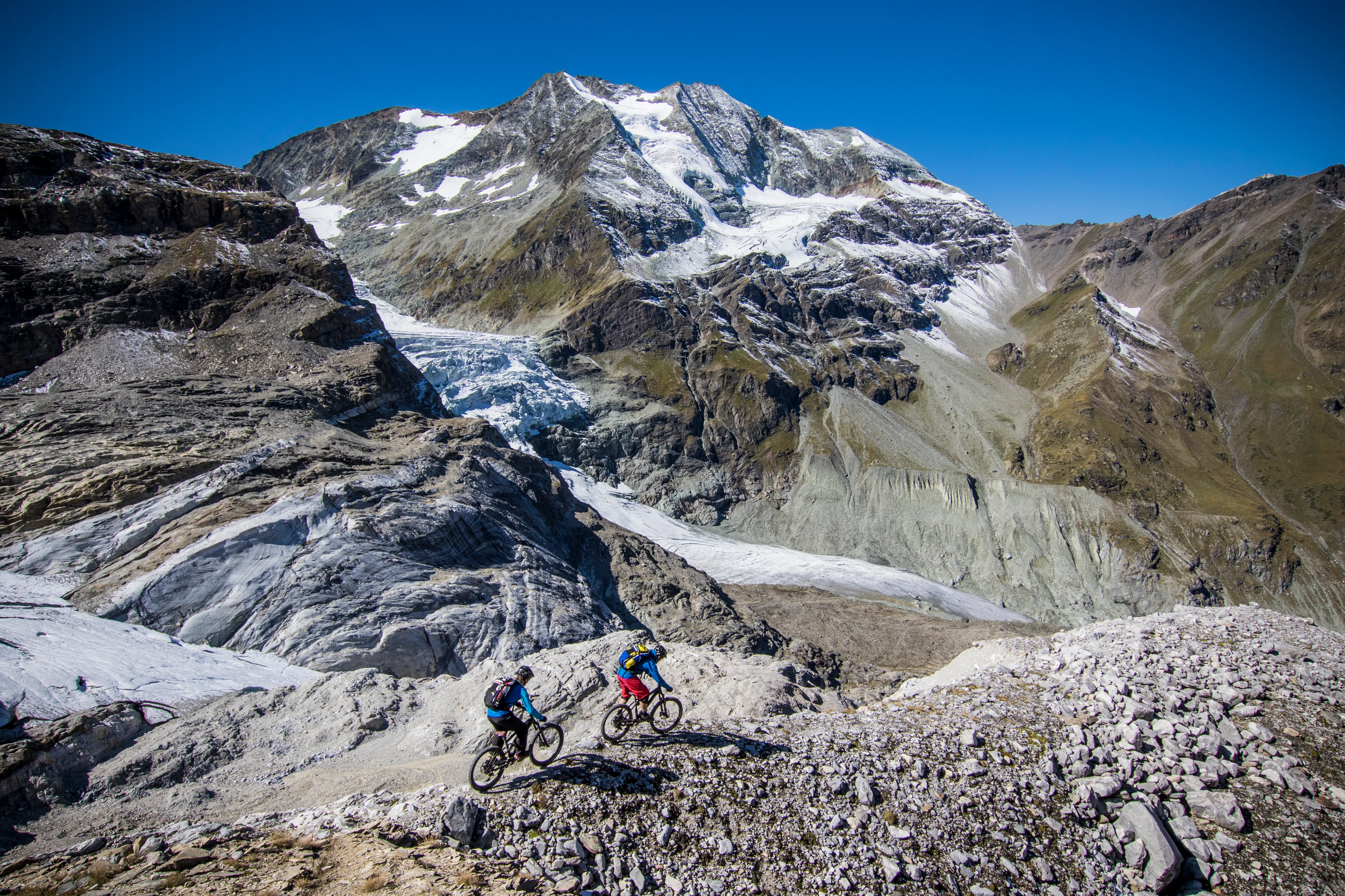 Robert Härle und Florian Häusler queren mit Mountainbikes eine hochalpine Bergflanke.