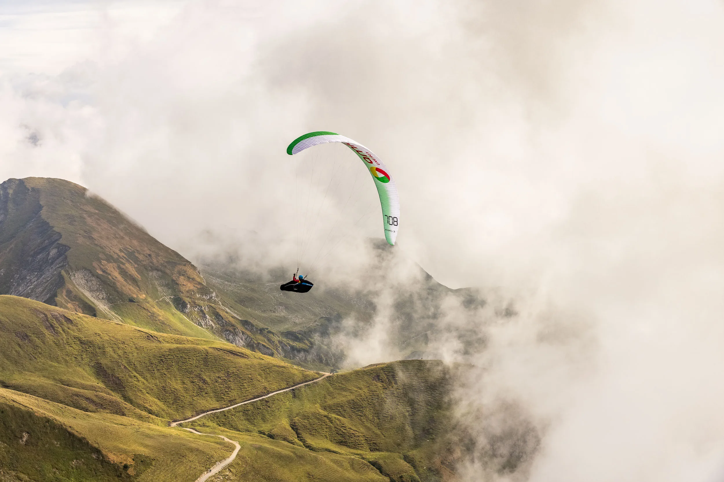 Klaudia Bulgakow fliegt mit ihrem Gleitschirm über einen wolkenverhangenen Grat am Nebelhorn.