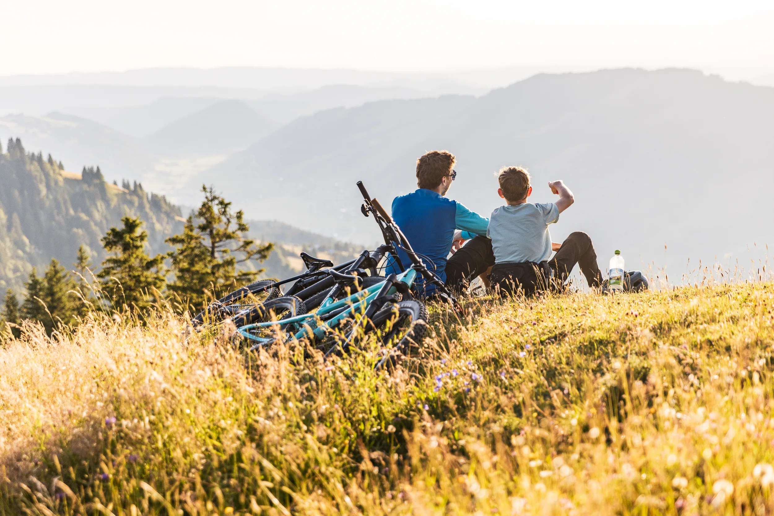 Zwei Mountainbiker sitzen neben ihren Rädern und blicken in die Allgäuer Berglandschaft