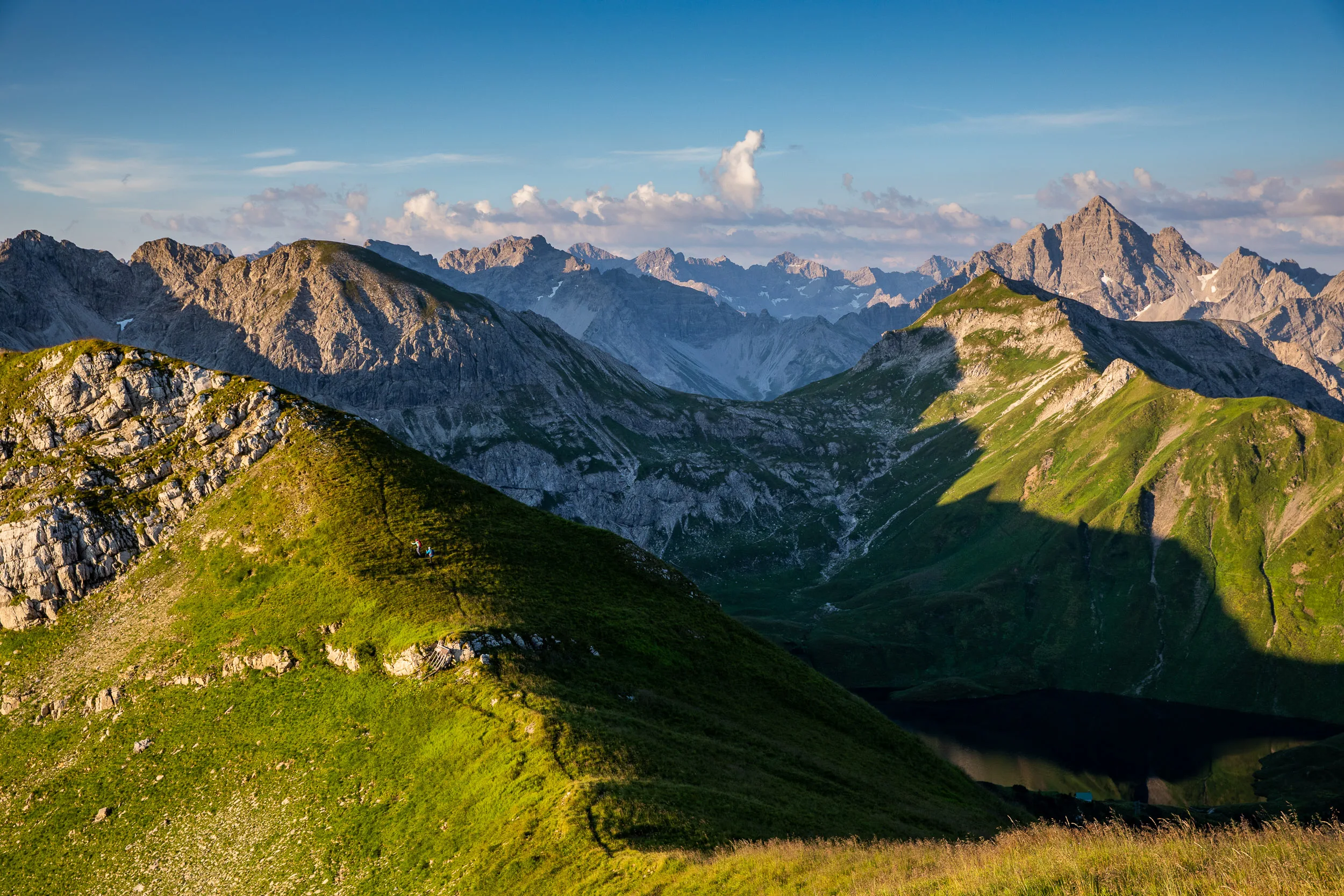 Sonnenlicht zeichnet grüne Bergrücken zwischen schroffen Gipfeln nach