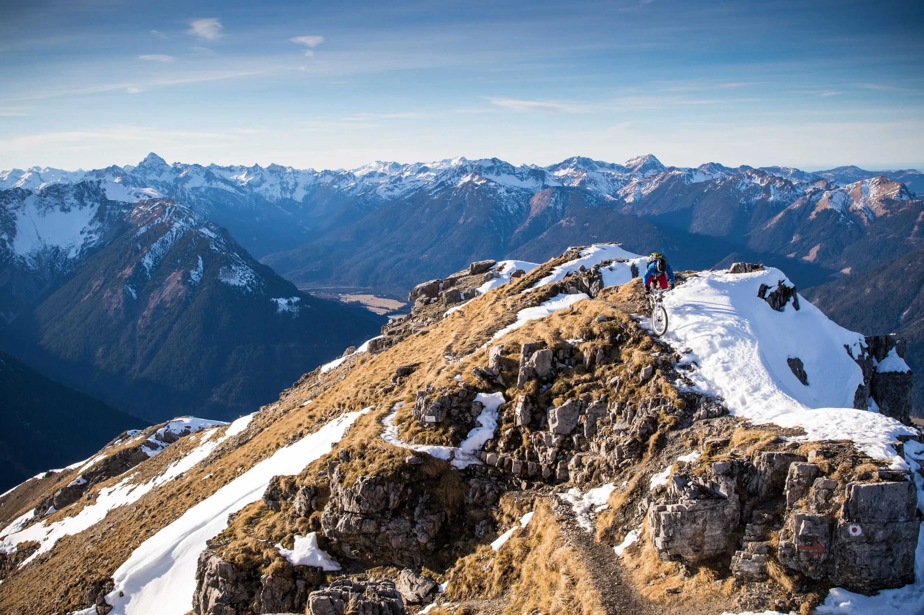 Florian Bergmann mit dem Mountainbike auf einem verschneiten Gipfelgrat am Thaneller.
