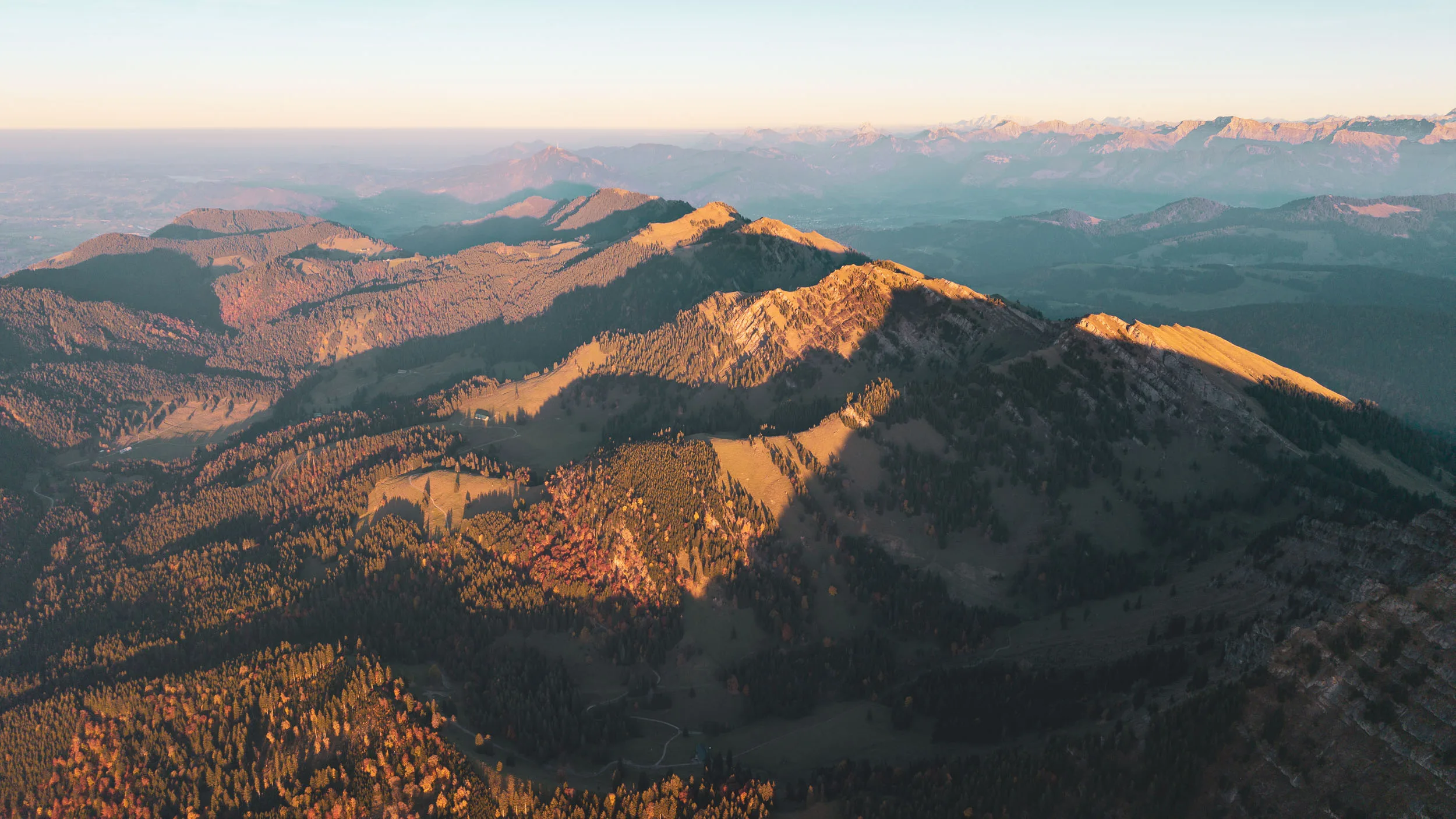 Mehrere Grate und Herbstwälder leuchten im letzten Sonnenlicht des Tages