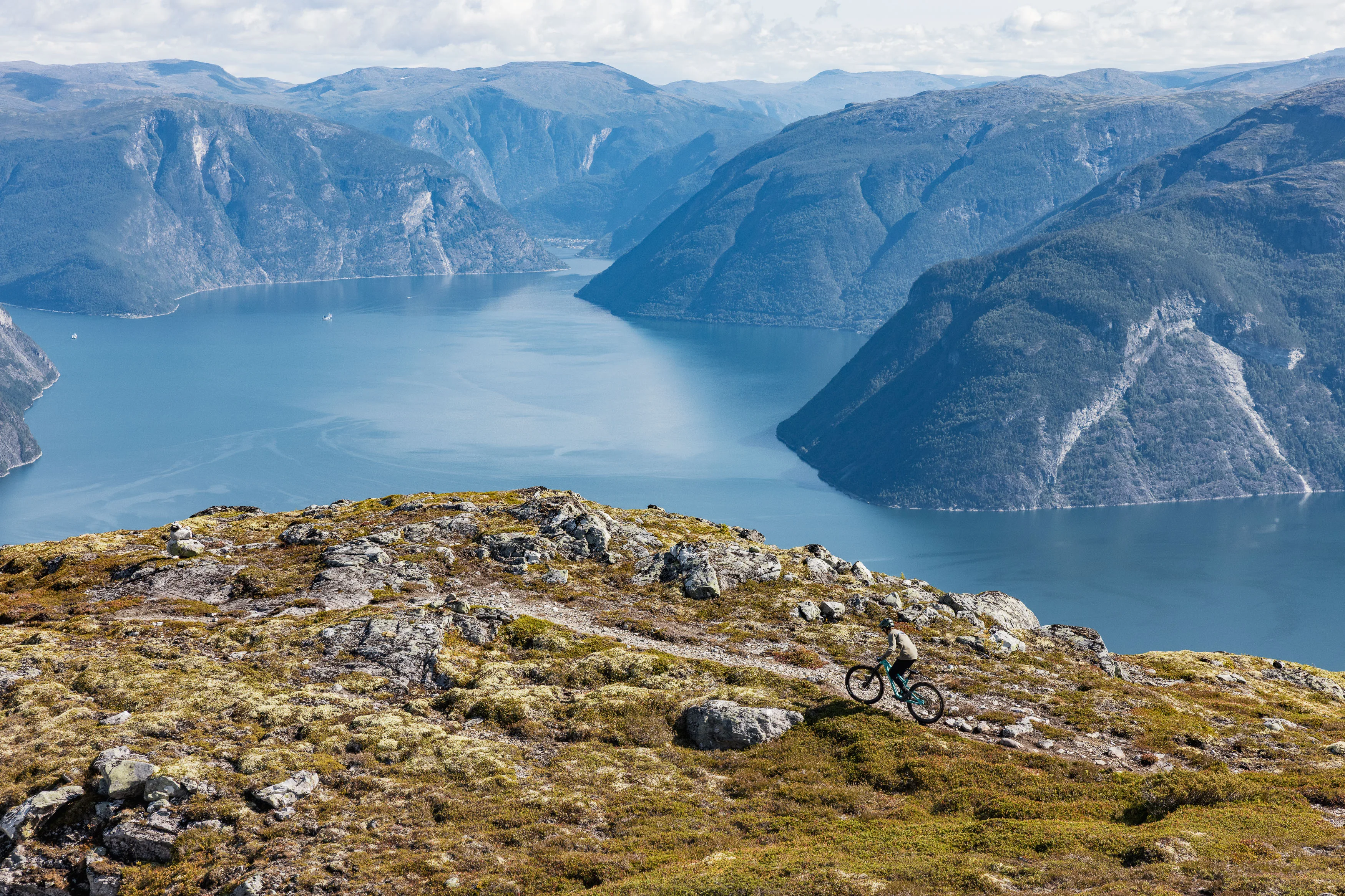 Mountainbiker folgt einem flachen Trail entlang eines Kamms über dem Fjord