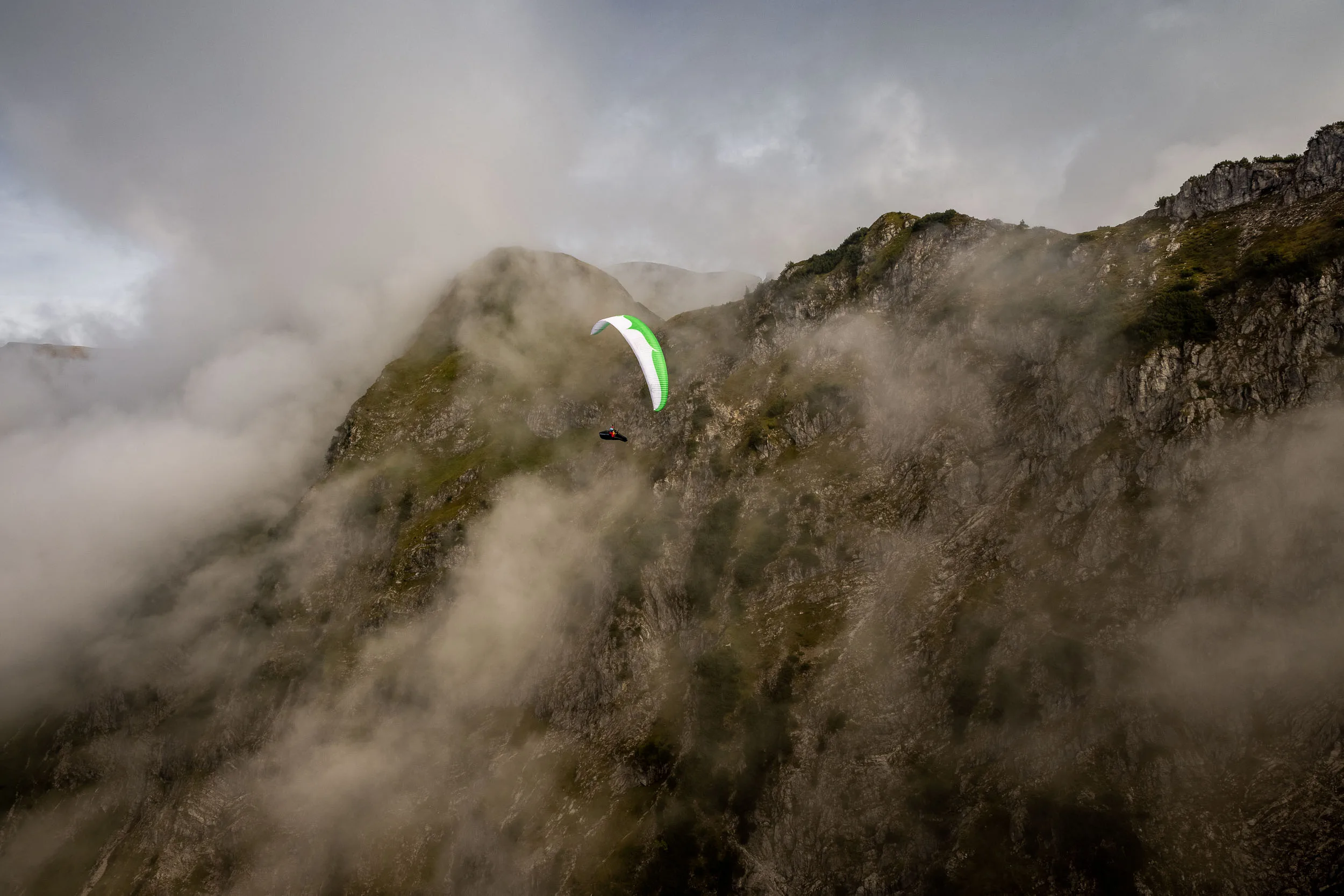 Klaudia Bulgakow fliegt mit ihrem Gleitschirm vor einer wolkigen Felswand am Nebelhorn.
