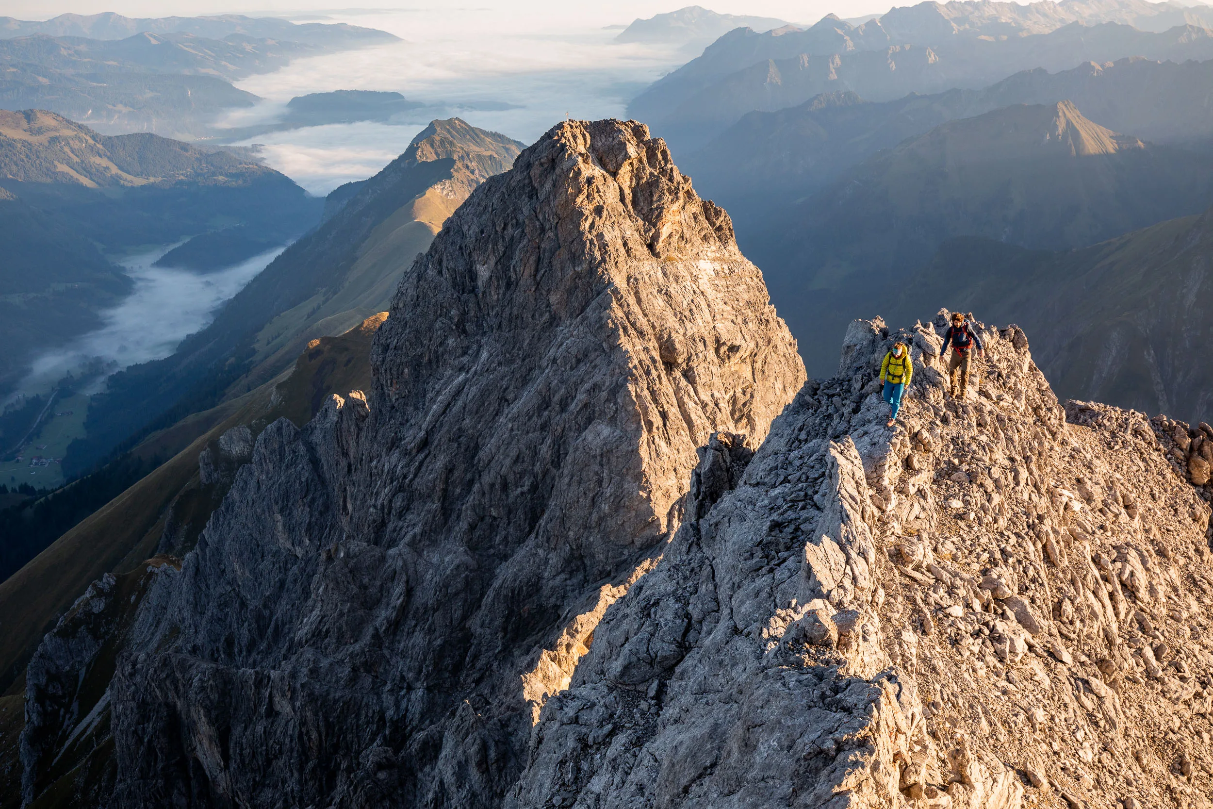 Raphaela Haug und Tom Besser steigen über einen sonnigen Felsgrat mit Blick ins Tal