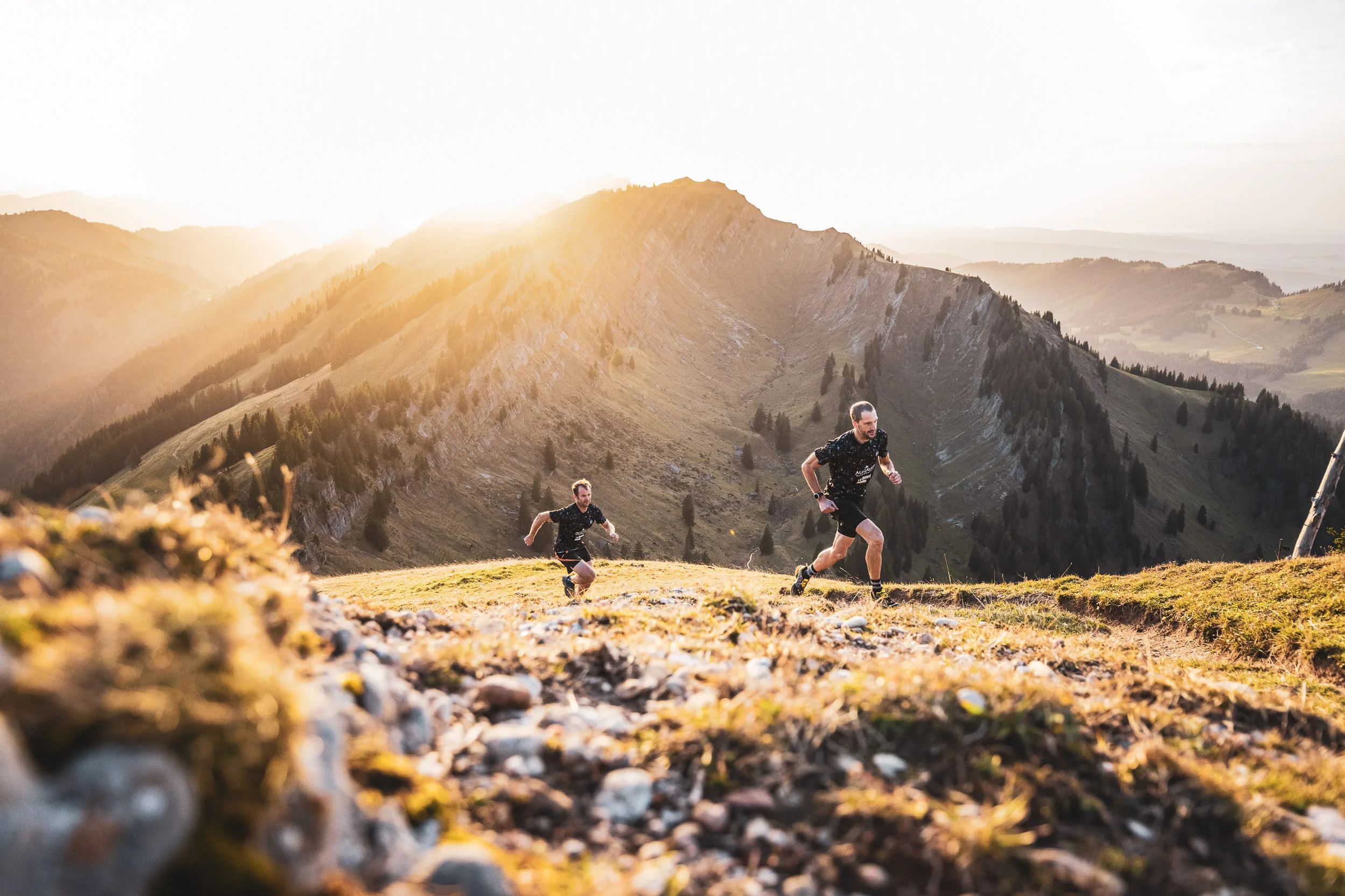 Trailrunner laufen vor einer hellen Bergkante der Nagelfluhkette