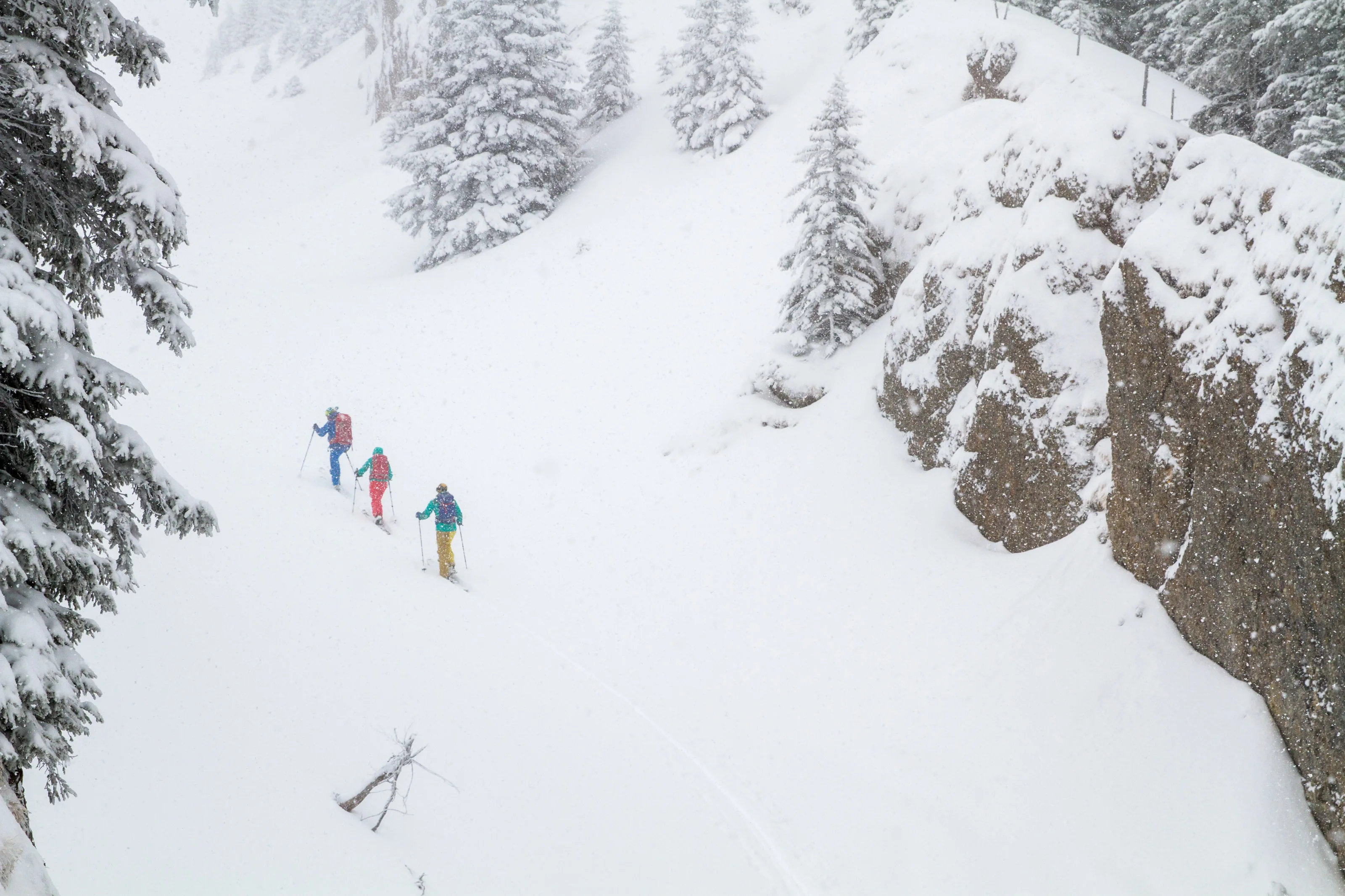 Skitourengeher folgen einer Spur unter einer schneebedeckten Felswand