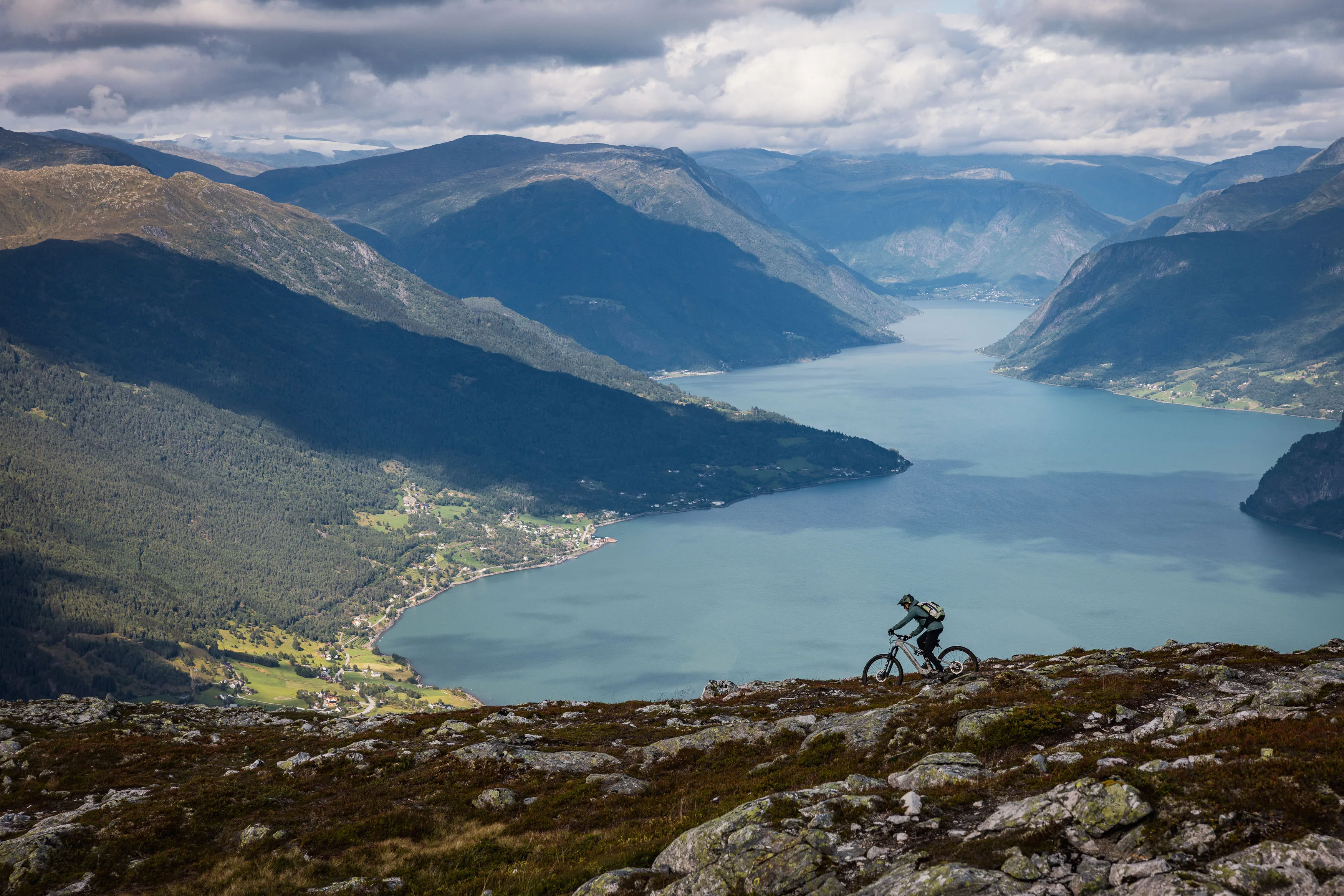 Mountainbiker fährt auf einer felsigen Linie hoch über einem norwegischen Fjord