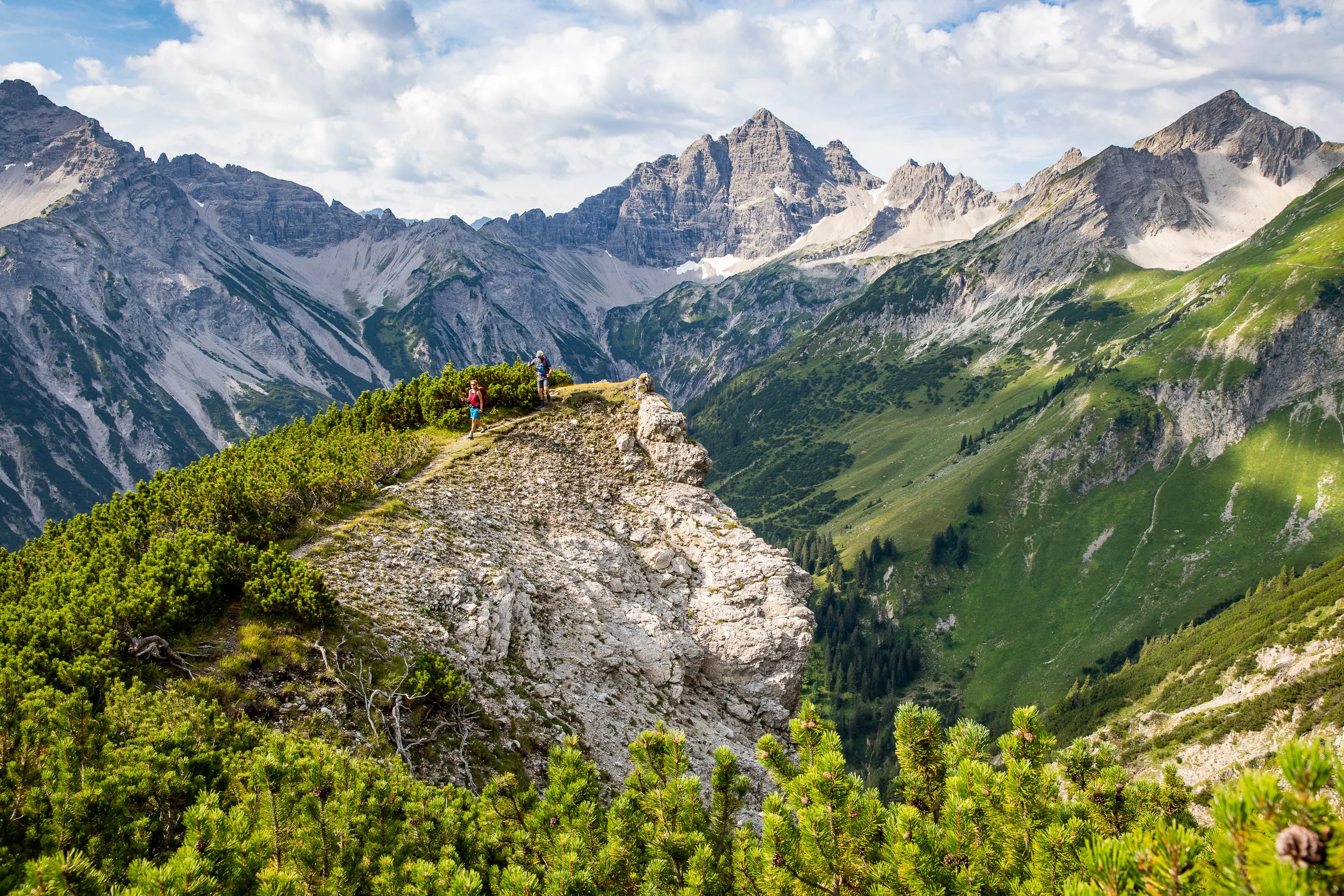 Ein felsiger Bergkopf liegt vor einer gestaffelten Gebirgskette