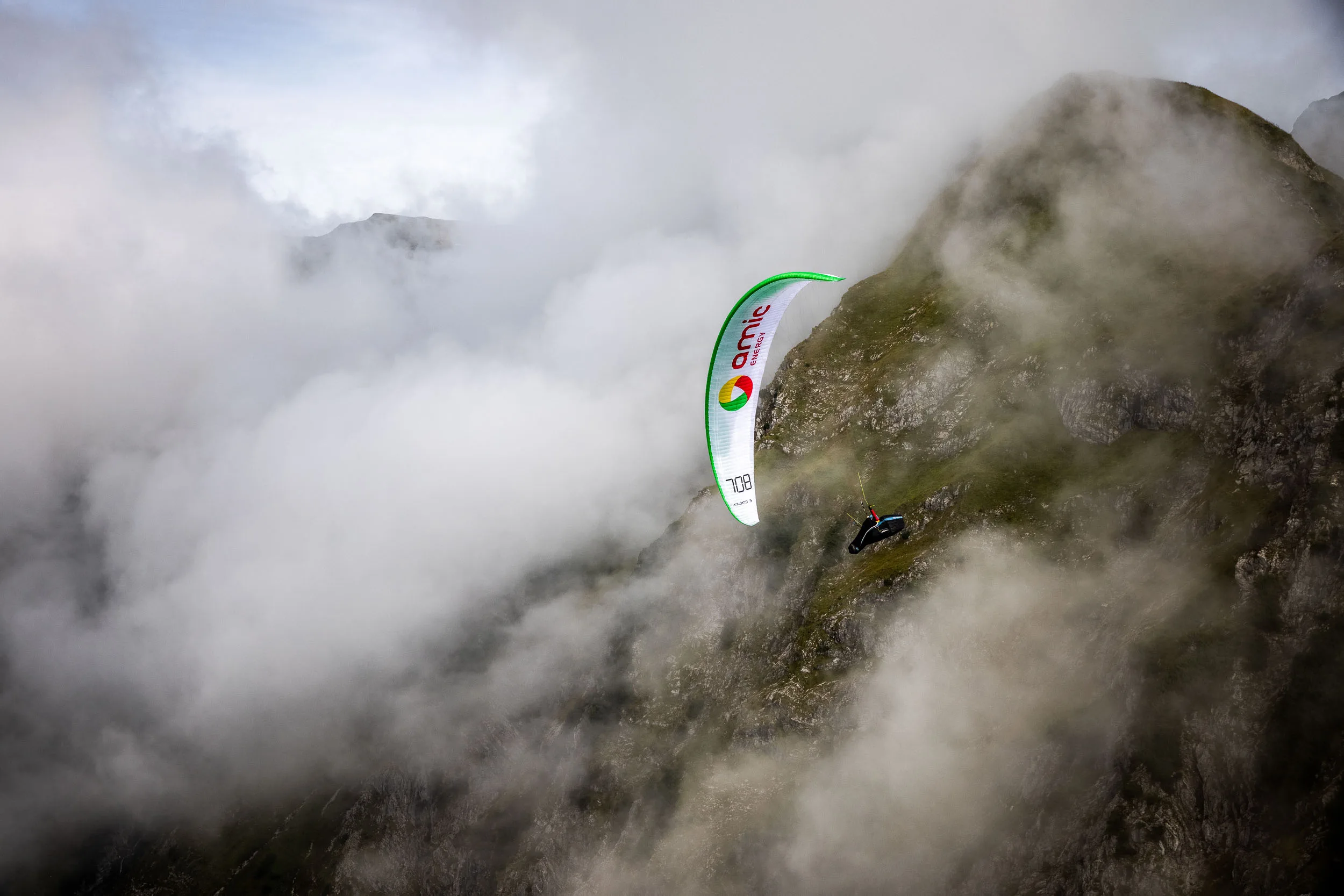 Klaudia Bulgakow fliegt mit ihrem Gleitschirm nah an einer Felswand im Nebel am Nebelhorn.