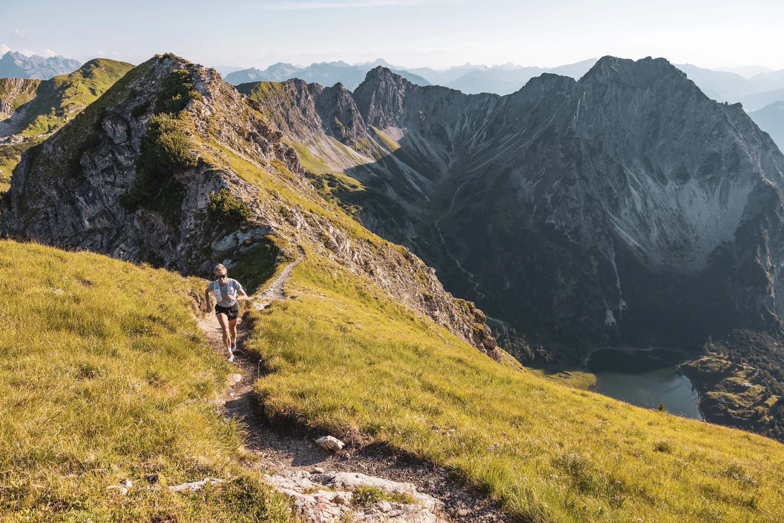 Ronja Morell läuft auf einem Bergpfad oberhalb eines Sees vor einer felsigen Bergkette