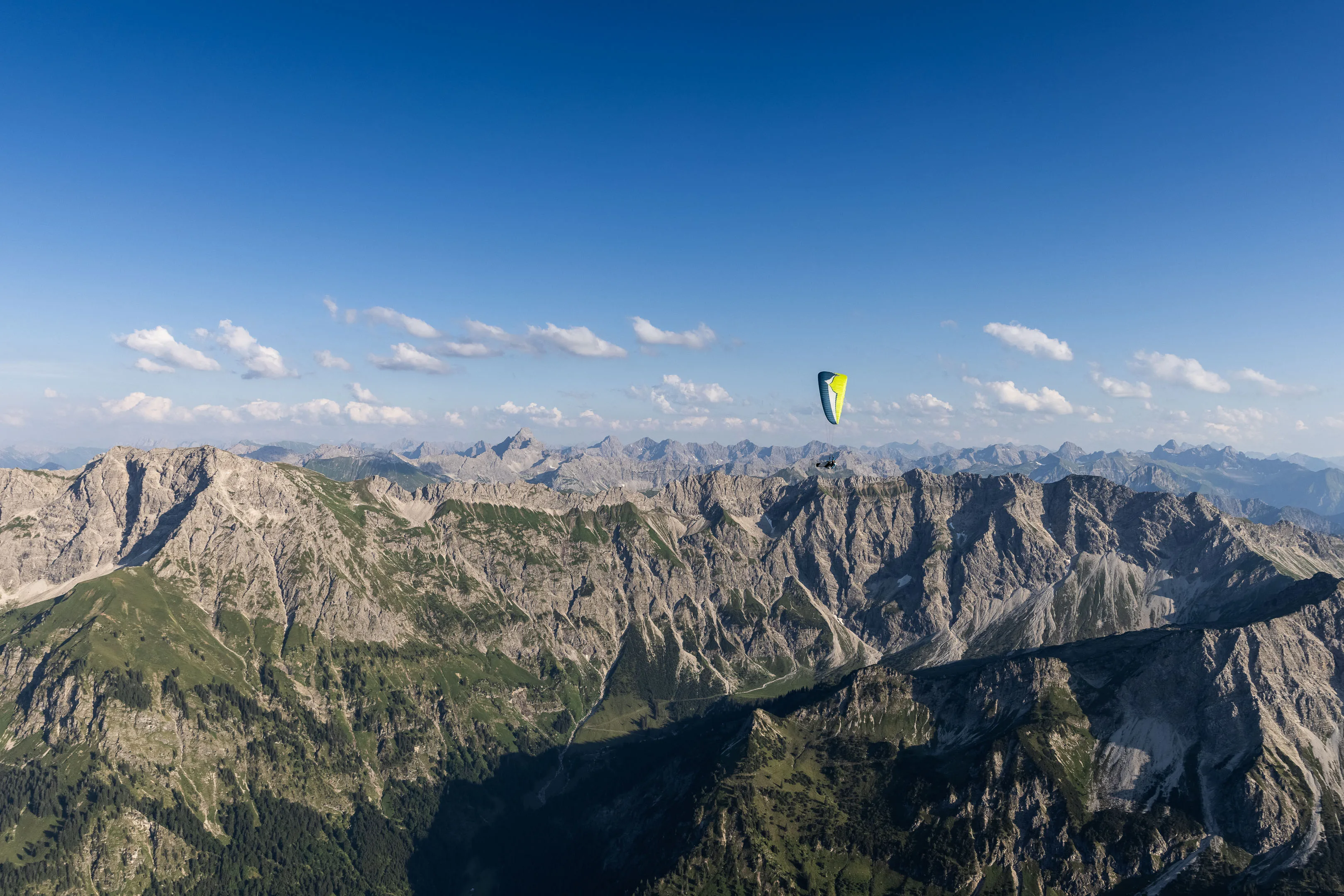 Michael Schnetzer fliegt klein vor der weiten Felskette der Allgäuer Alpen