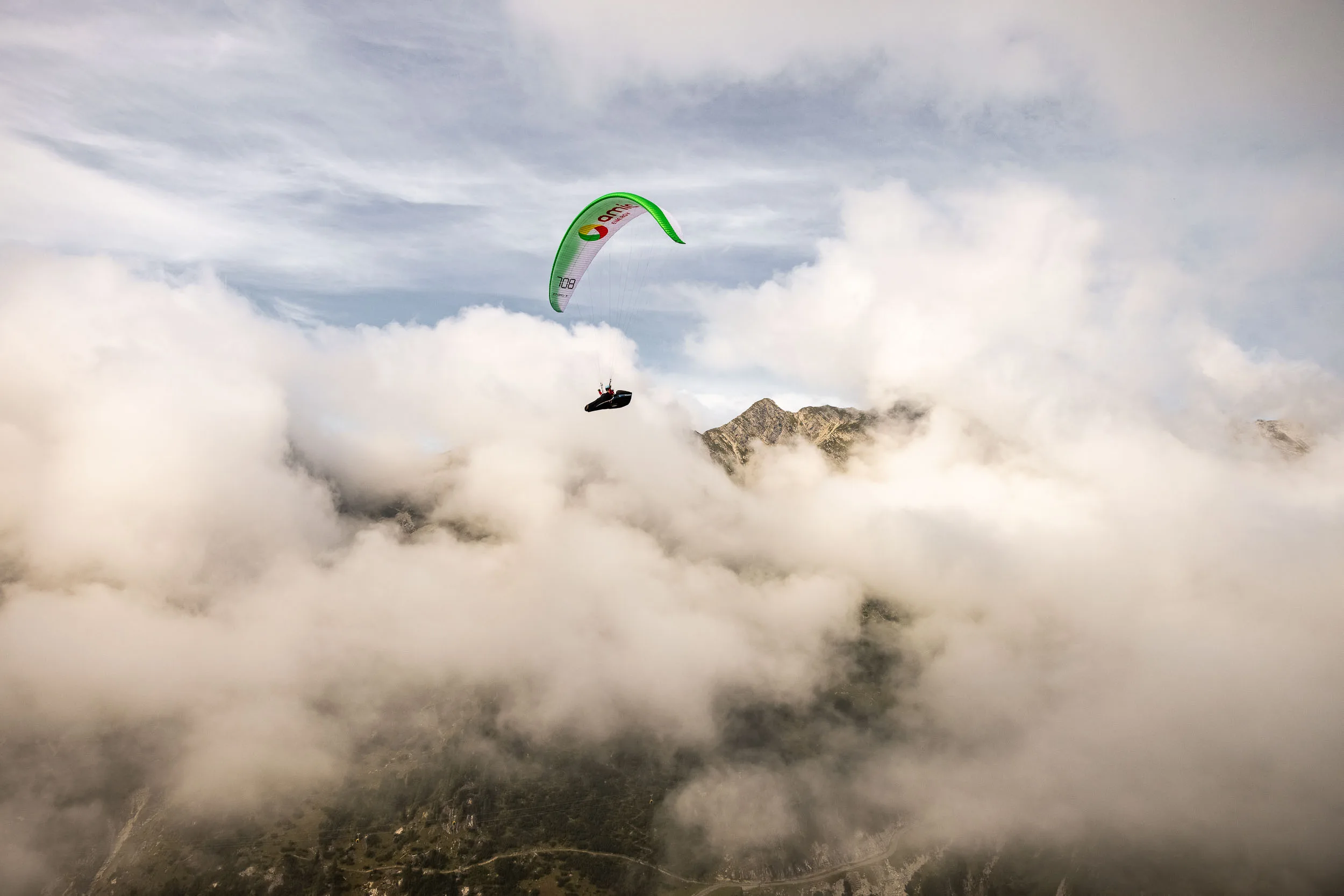 Klaudia Bulgakow fliegt mit ihrem Gleitschirm zwischen Wolken und Gipfeln am Nebelhorn.