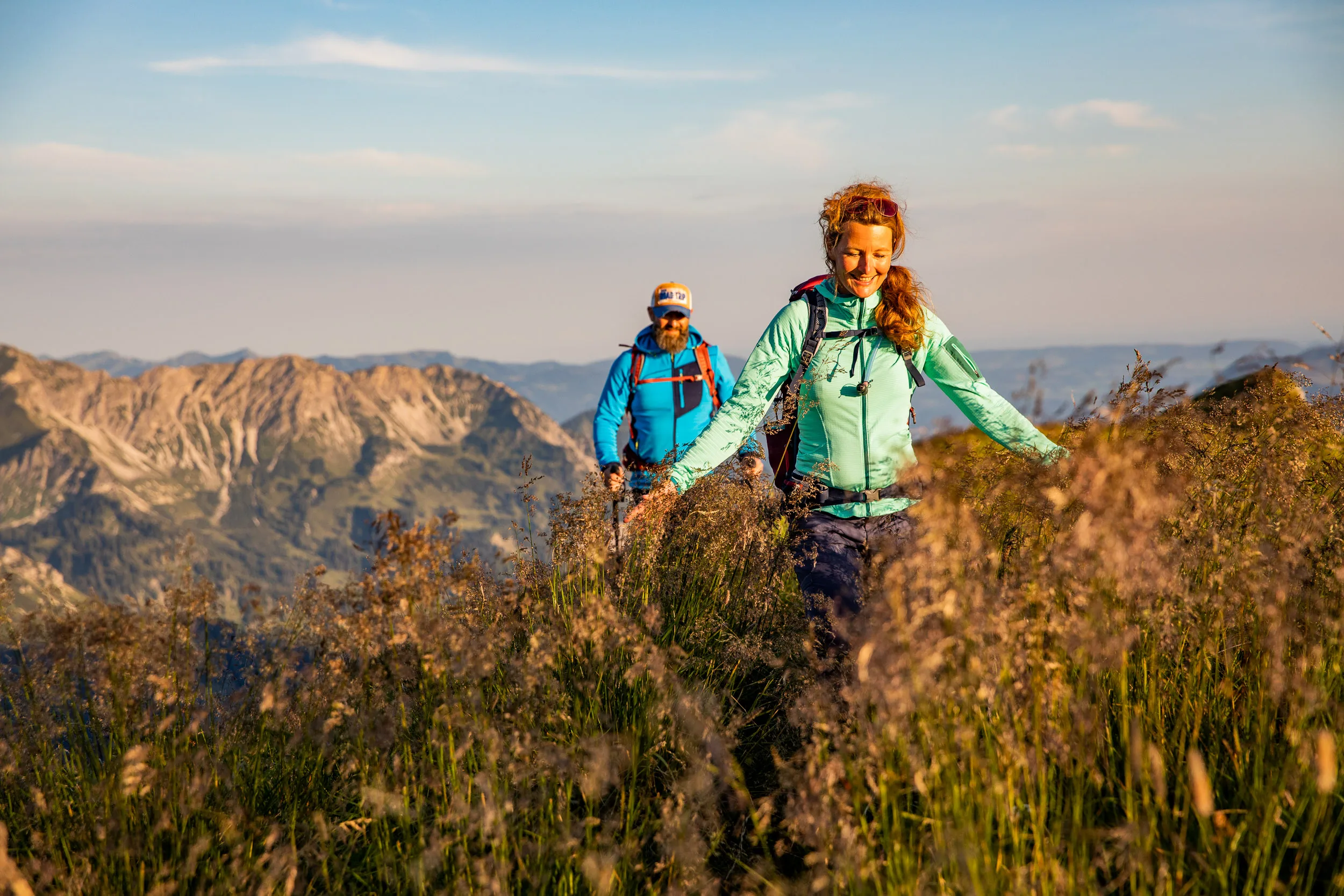 Caroline Nantke und Harald Dreyer wandern durch eine blühende Wiese vor schroffen Gipfeln