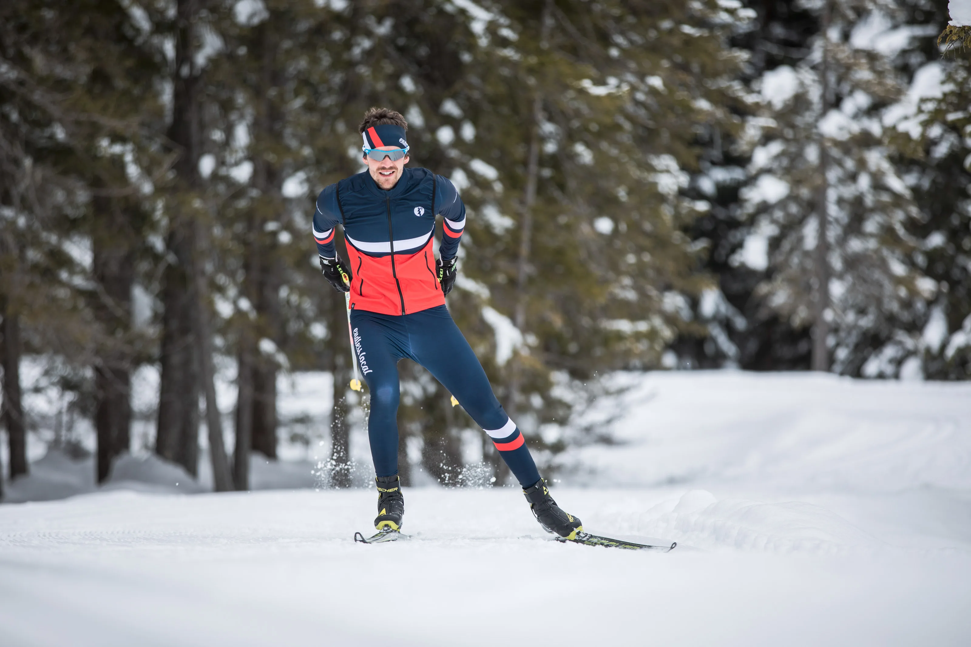 Michael Schnetzer beim Skating-Langlauf vor unscharfen Schneezweigen im Vordergrund.