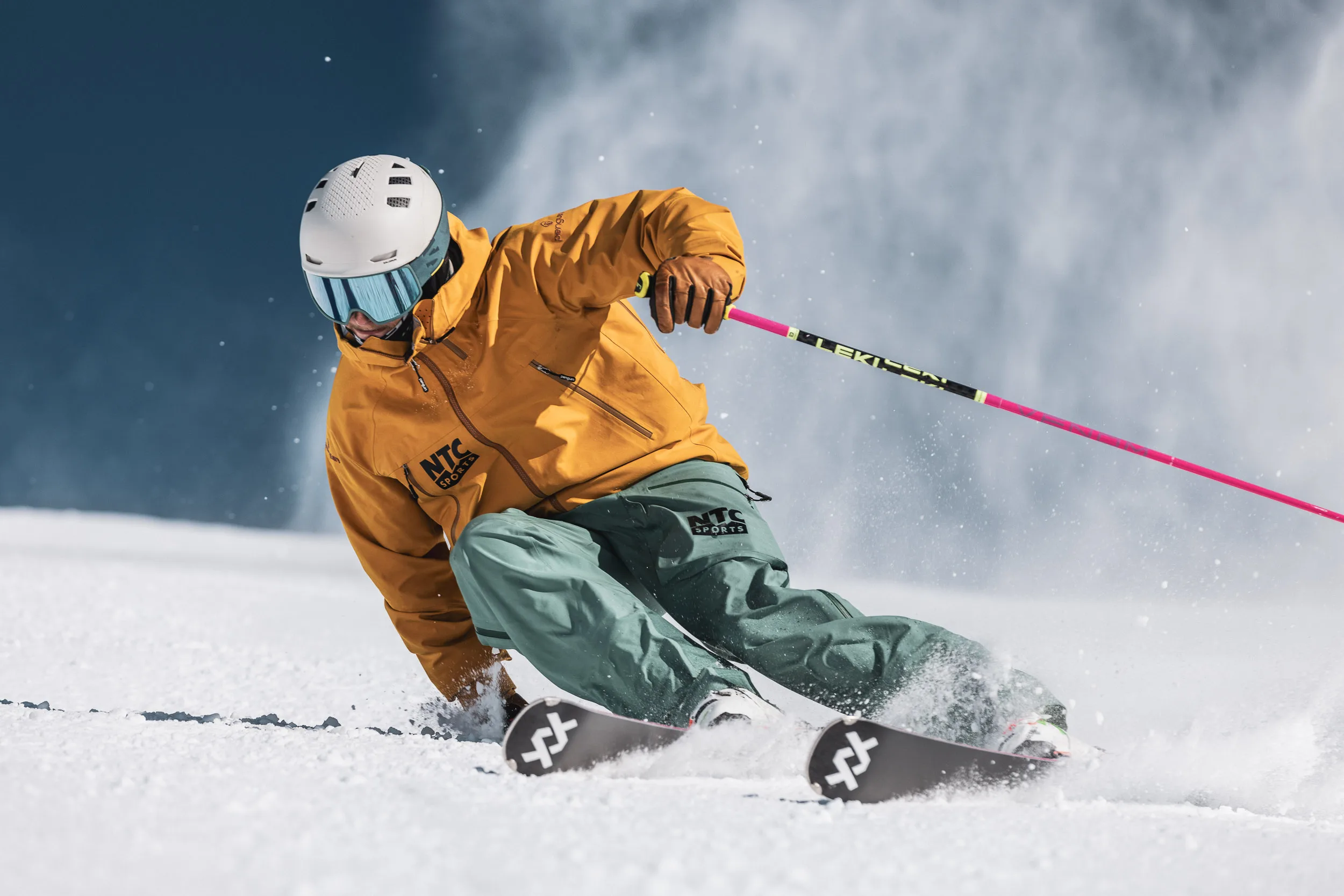Skilehrer fährt in enger Kurve mit aufspritzendem Schnee