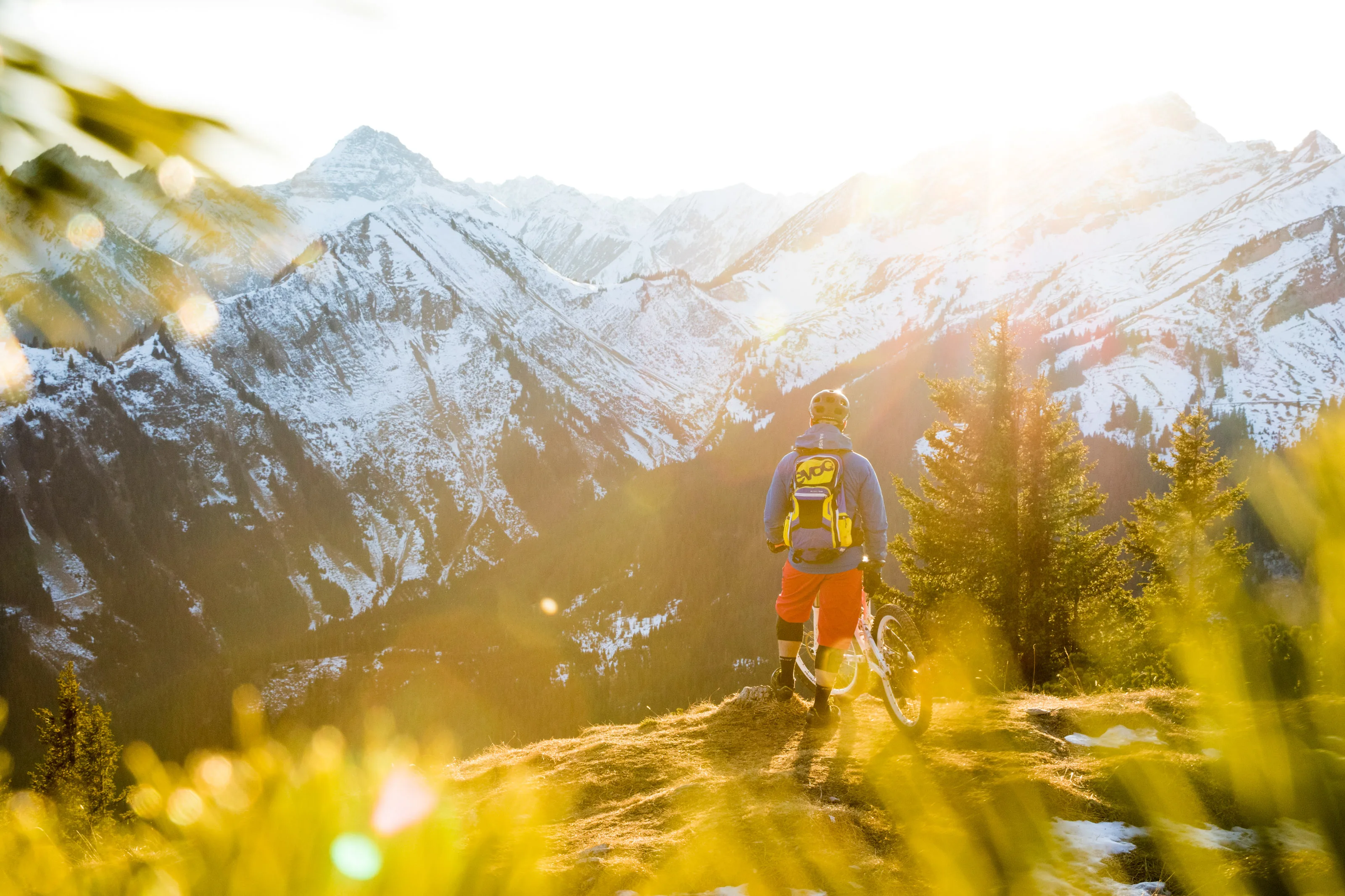 Florian Bergmann steht mit seinem Mountainbike vor verschneiten Bergen am Thaneller.