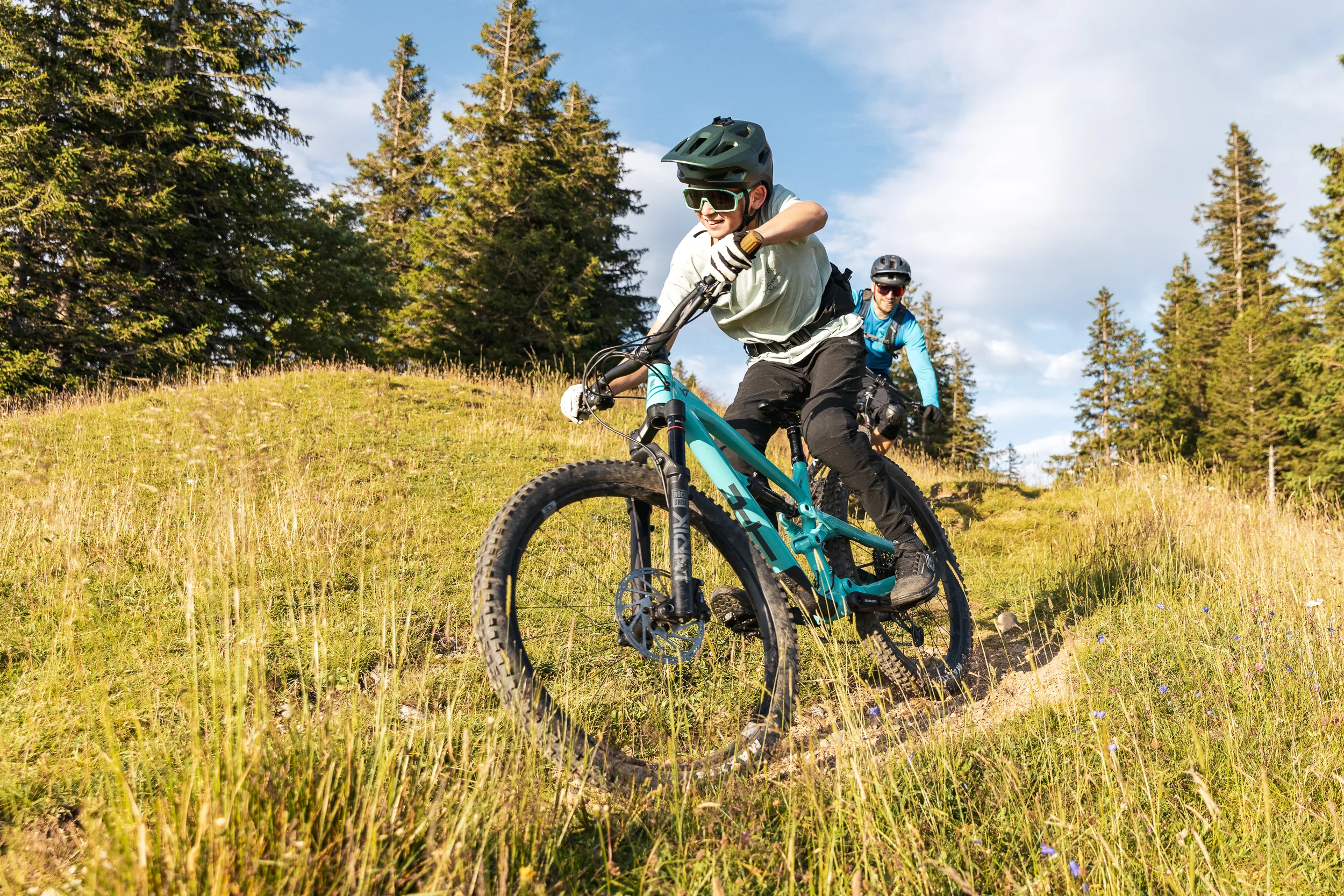 Mountainbiker steuert sein Rad durch eine enge Kurve auf dem Wiesenpfad