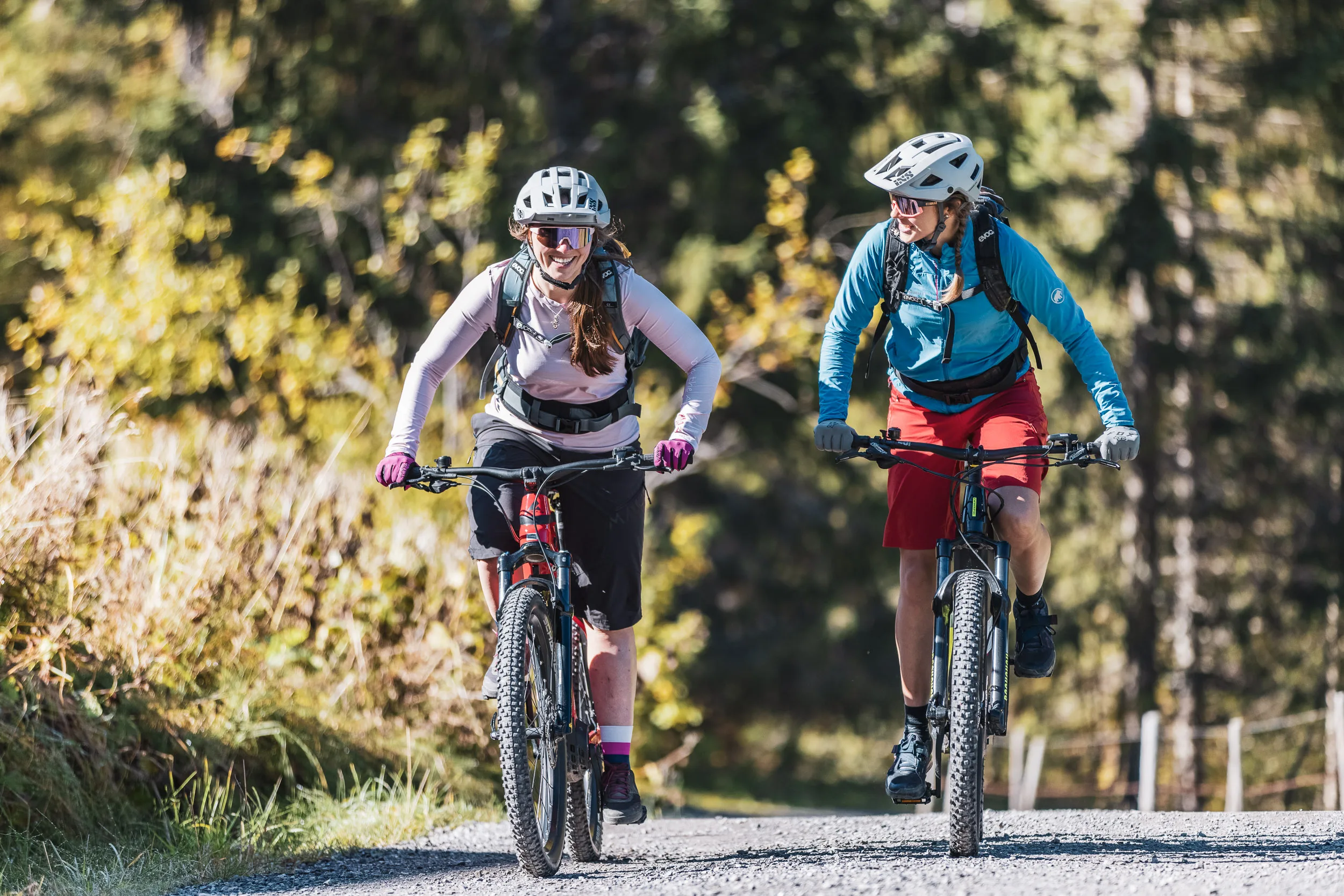 Silvi Vogel und Andrea Geiger fahren auf einer Forststraße durch herbstliche Wälder