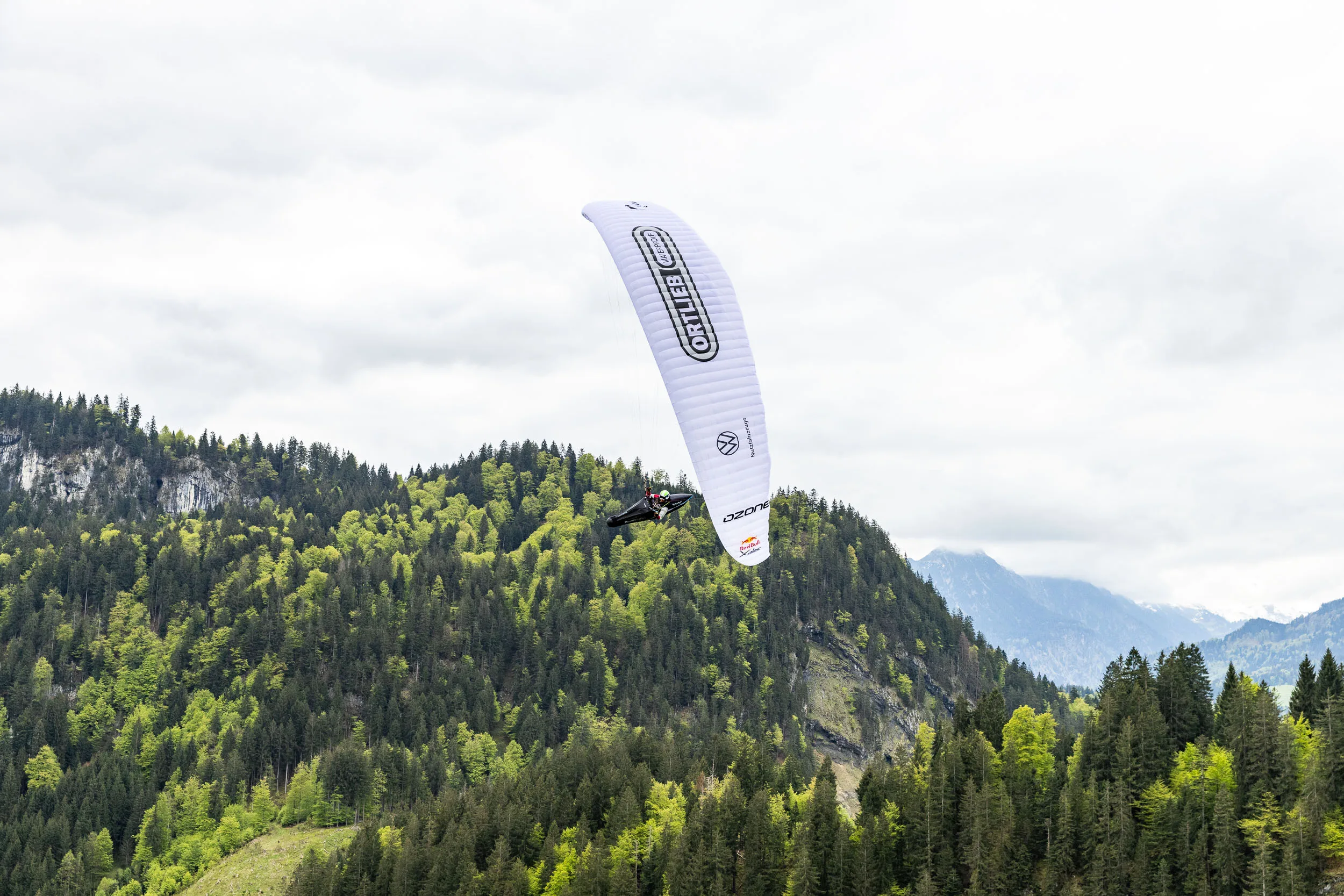 Eli Egger gleitet mit Gleitschirm ueber Wald und Berge im Allgaeu.
