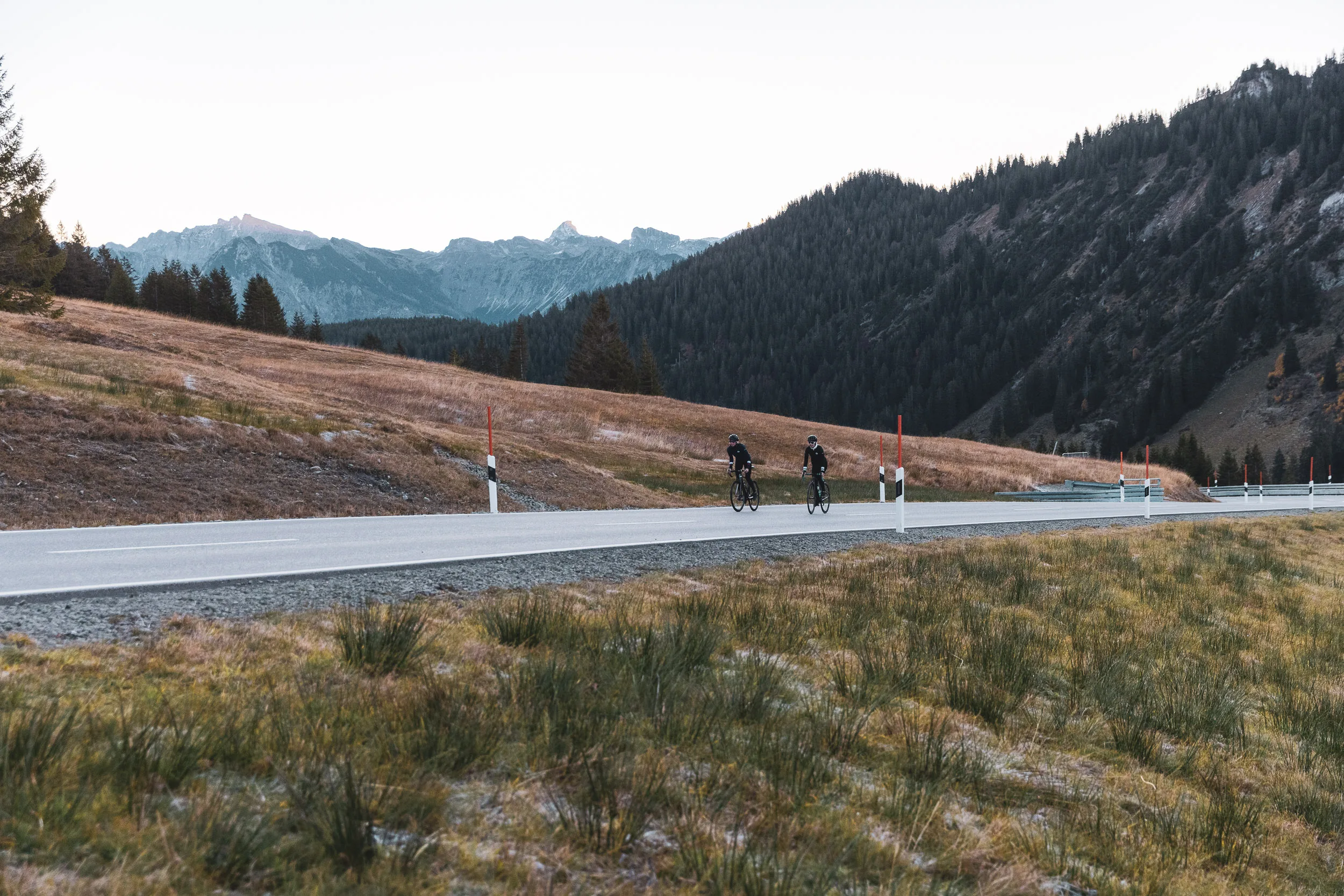 Zwei Rennradfahrerinnen fahren klein im Bild durch die Berglandschaft