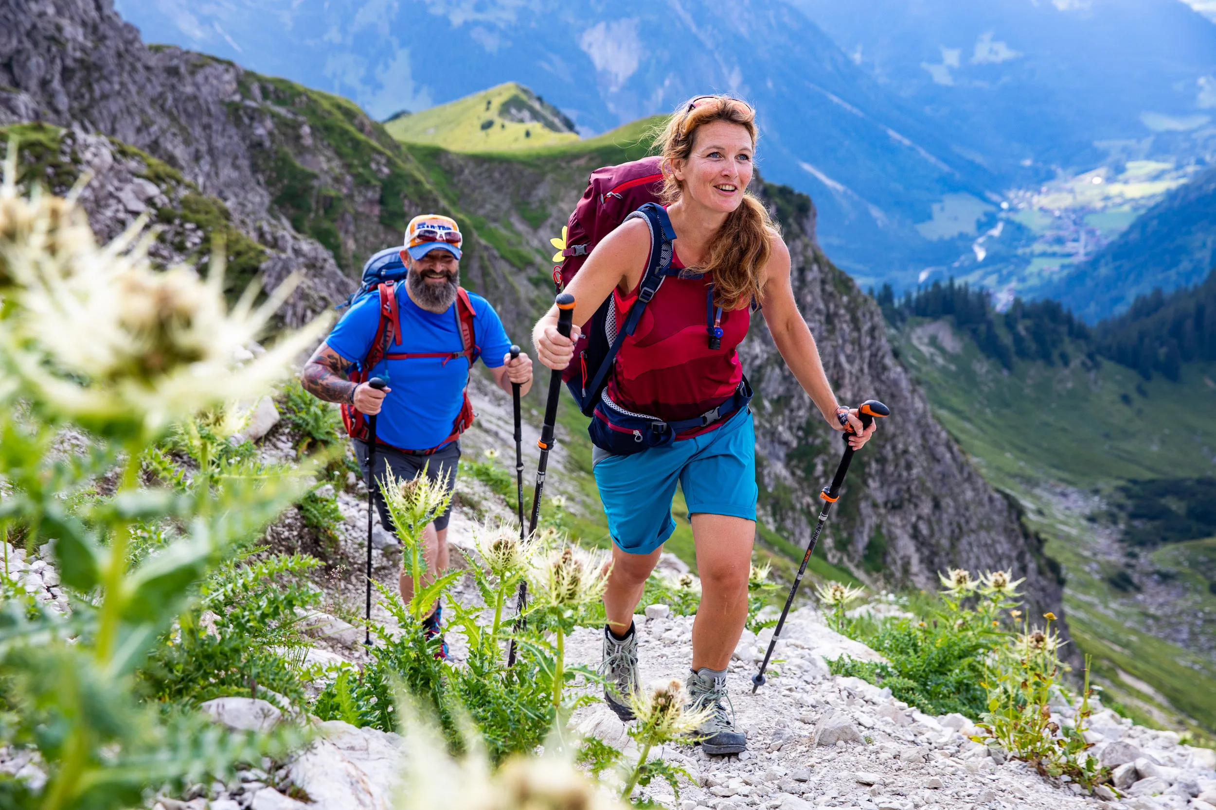 Caroline Nantke führt auf einem Bergpfad durch blühende Hänge oberhalb des Tals
