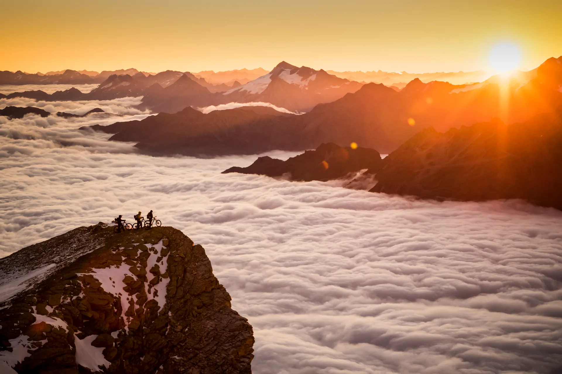 Mountainbiker stehen mit ihren Rädern über einem Wolkenmeer am Barrhorn.