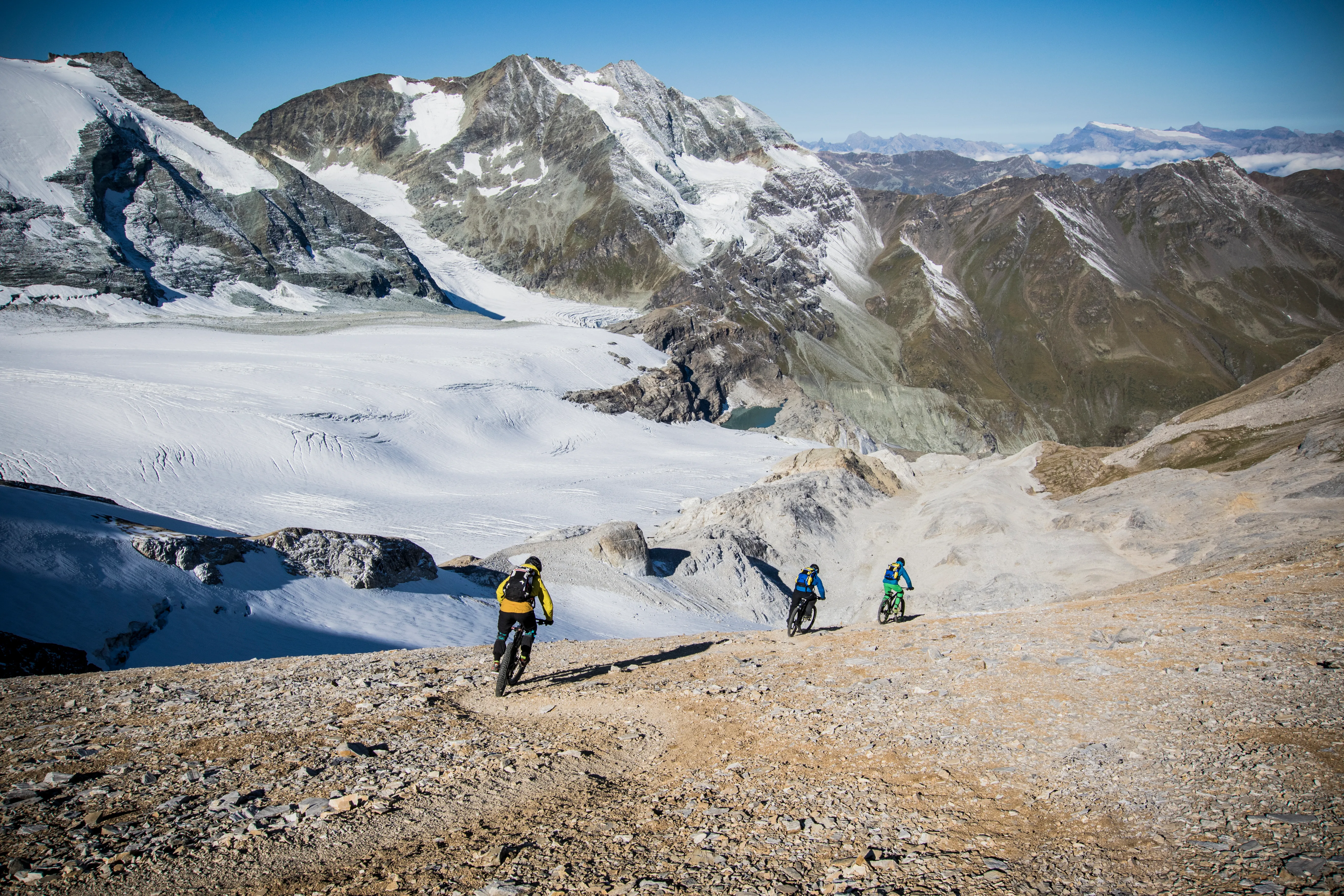 Robert Härle, Florian Bergmann und Florian Häusler erreichen mit ihren Mountainbikes einen Gipfelgrat.