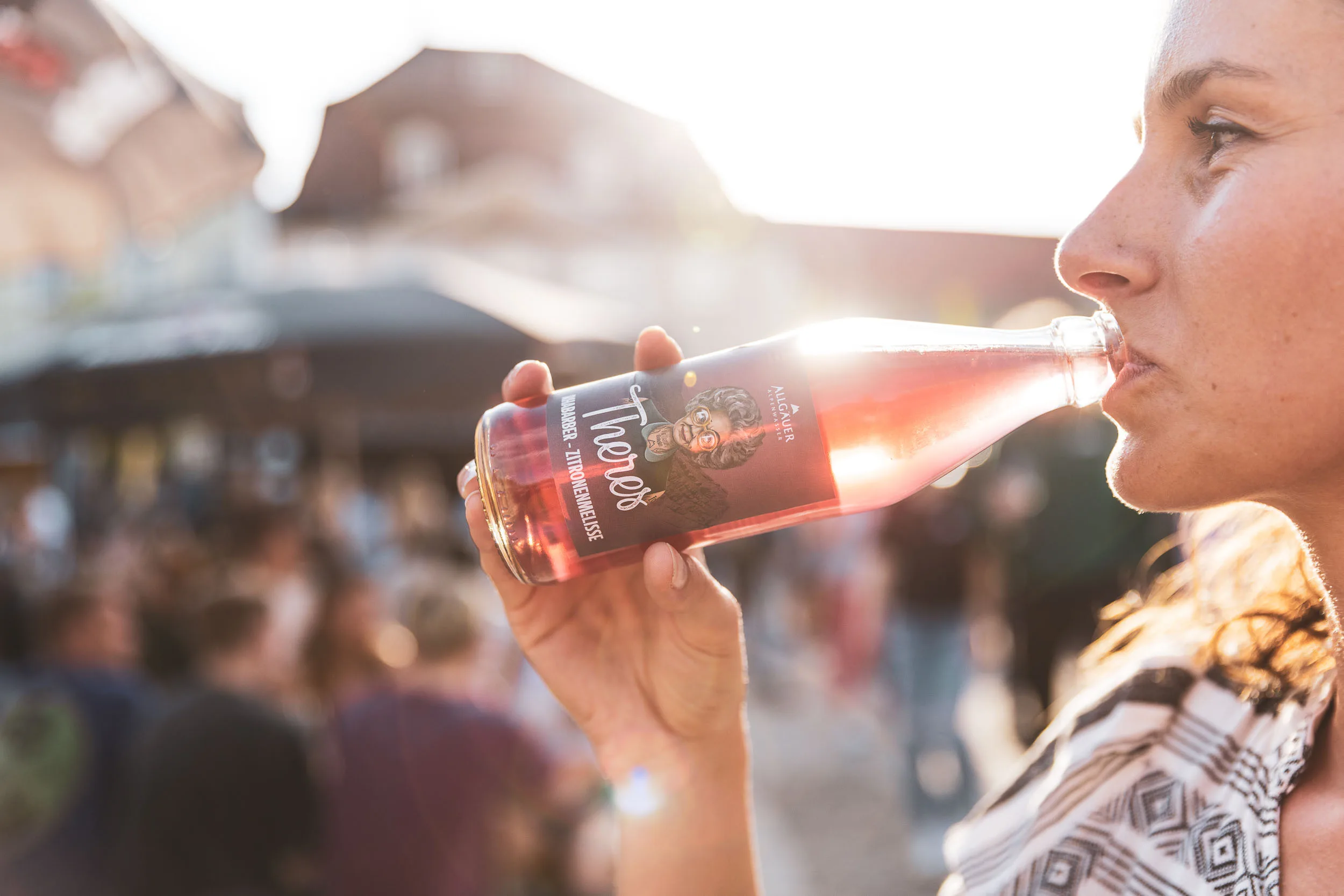 Person trinkt aus einer Flasche vor dem Marktgeschehen.