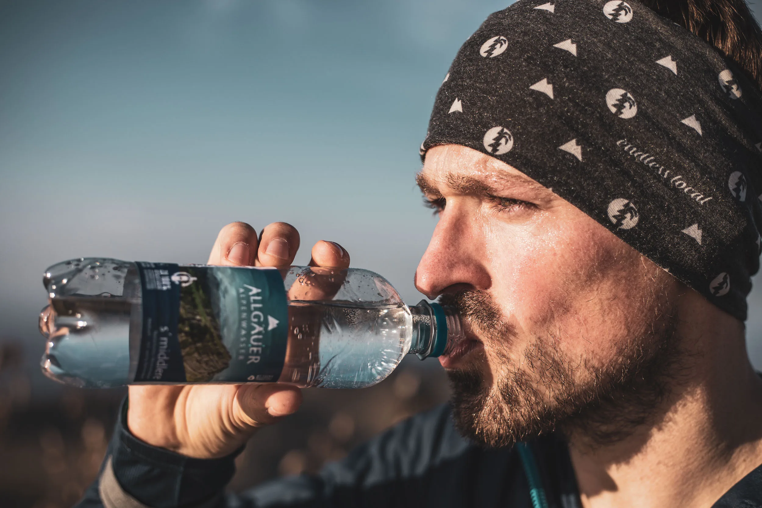 Andreas Kögel trinkt an einem sonnigen Gratweg während eines Trailruns in der Nagelfluhkette.