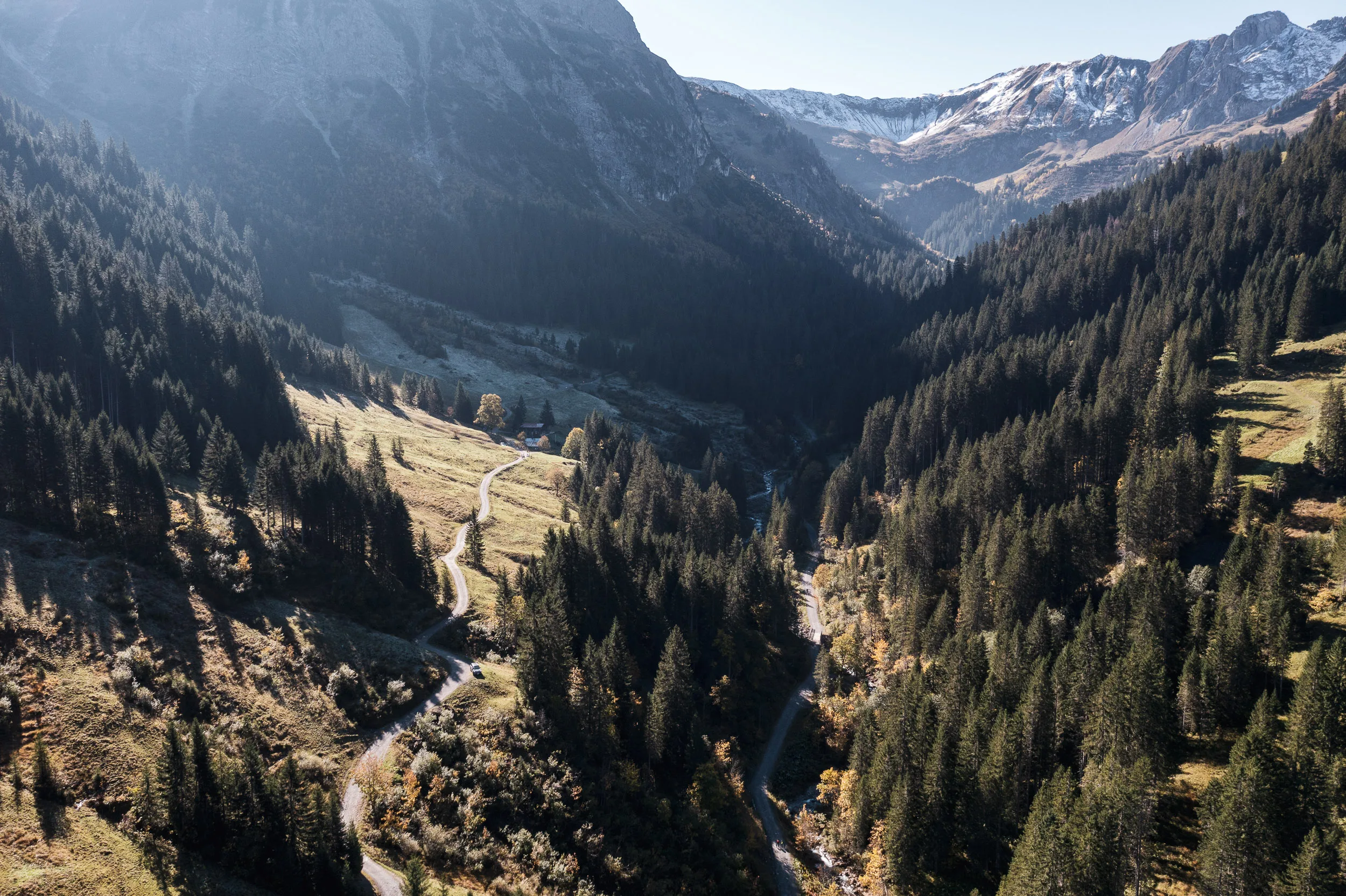 Luftaufnahme eines bewaldeten Bergtals mit herbstlichen Almen im Kleinwalsertal