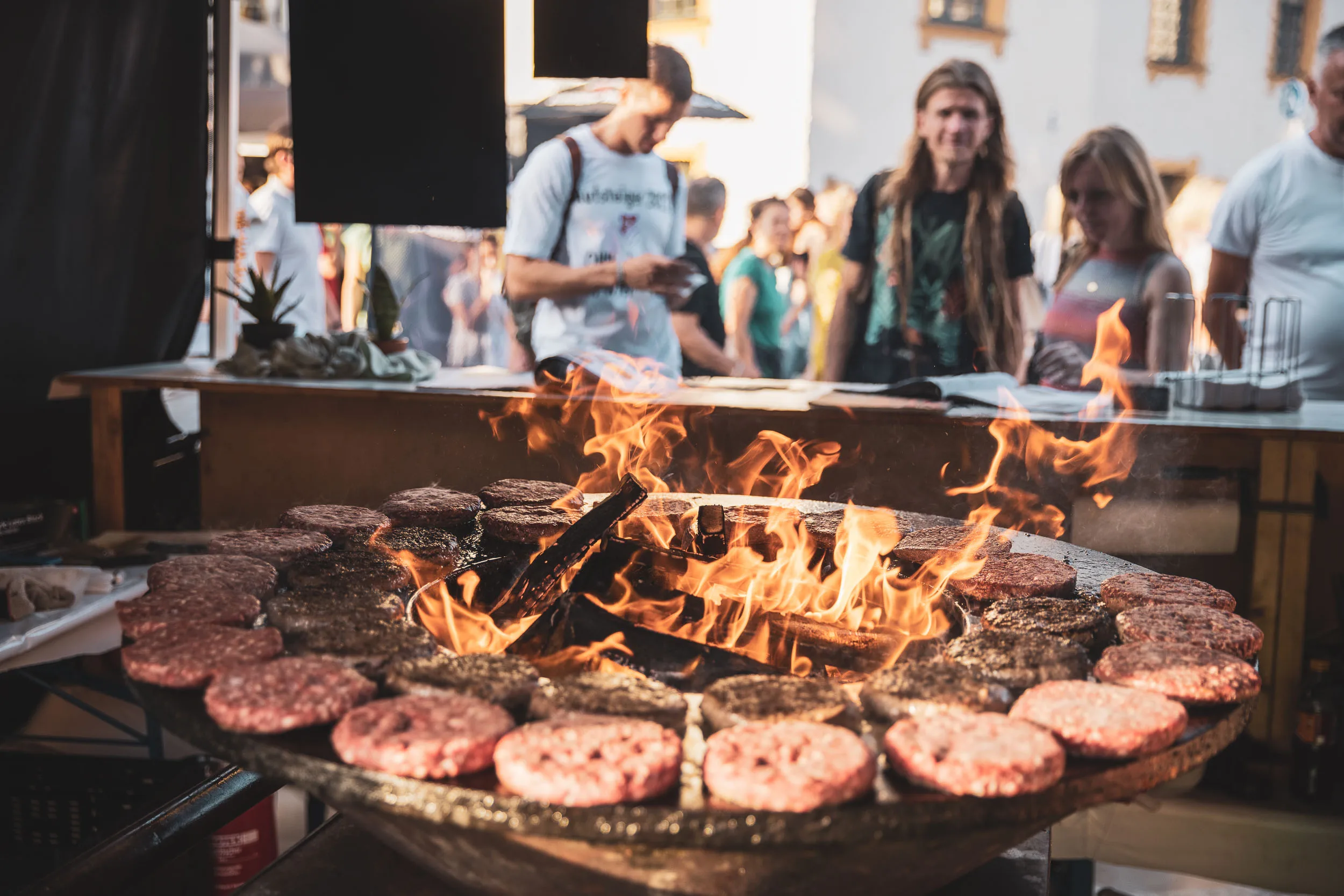 Burger-Patties brutzeln auf einem Grill des Street Food Markts.