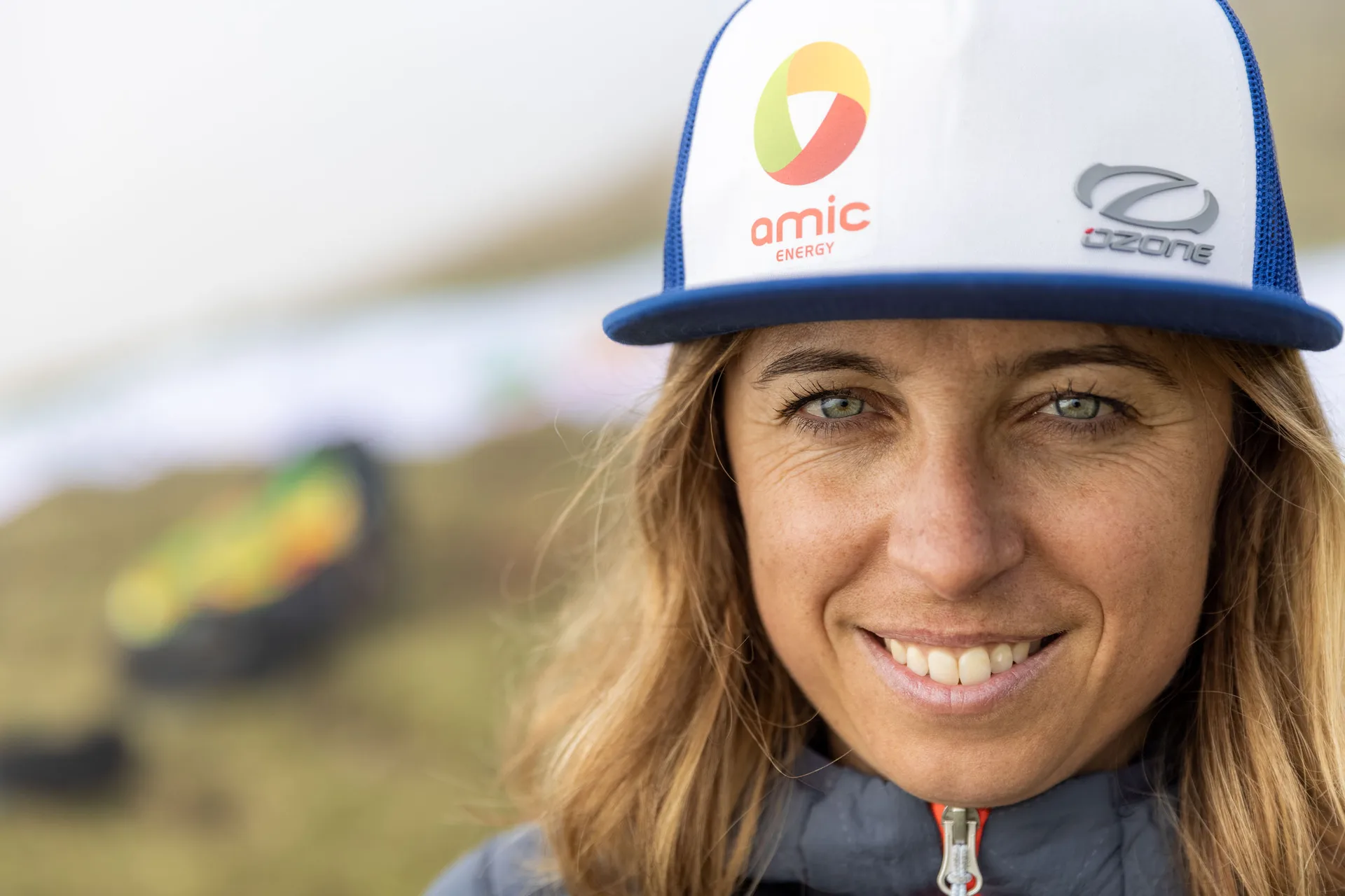 Klaudia Bulgakow lächelt frontal in die Kamera; sie trägt eine weiß-blaue Kappe mit Ozone- und Amic-Energy-Logo.