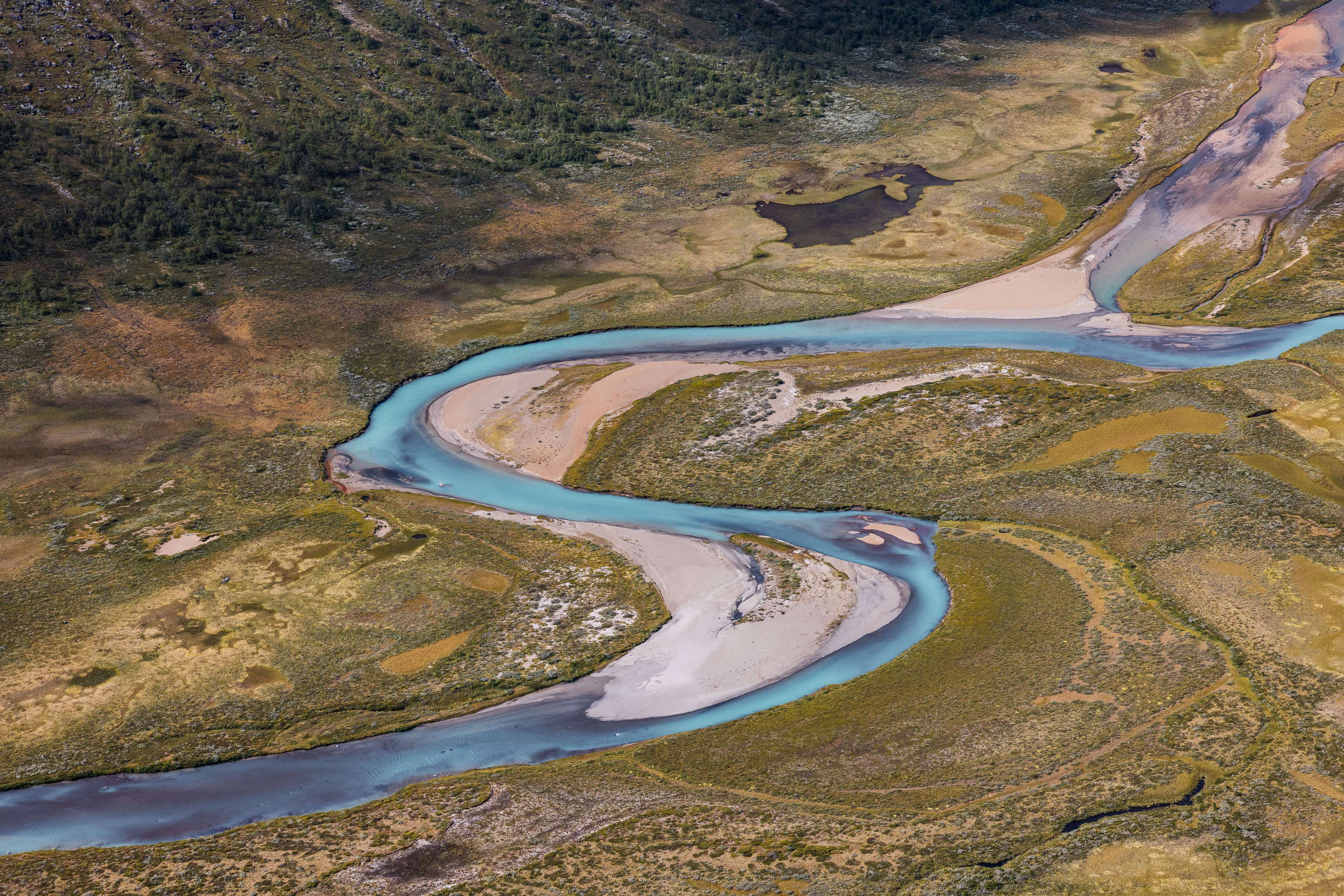 Türkisfarbener Fluss windet sich durch eine karge Hochlandebene