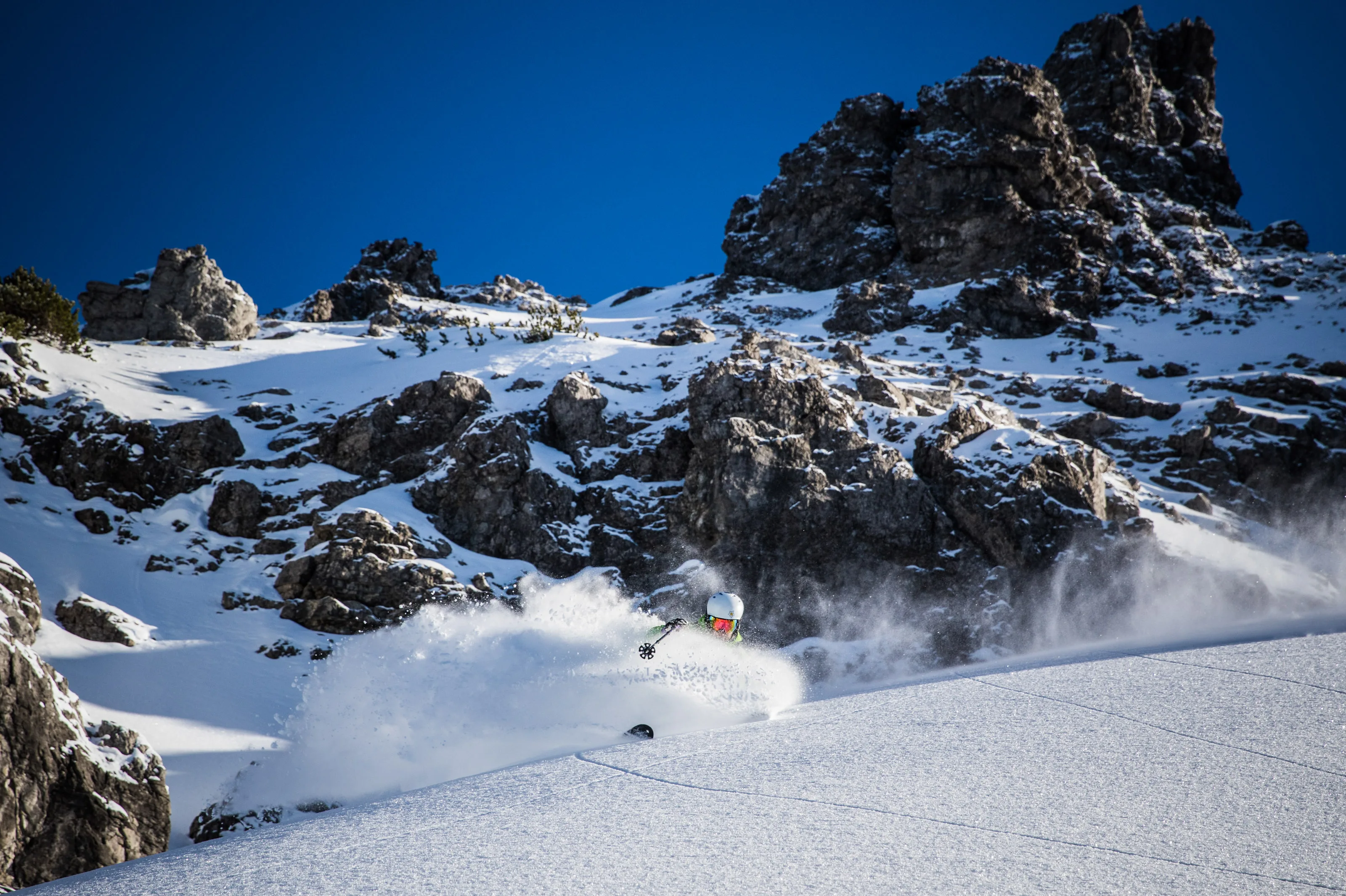 Florian Bergmann beim Skifahren durch Pulverschnee unter Felsen am Thaneller.
