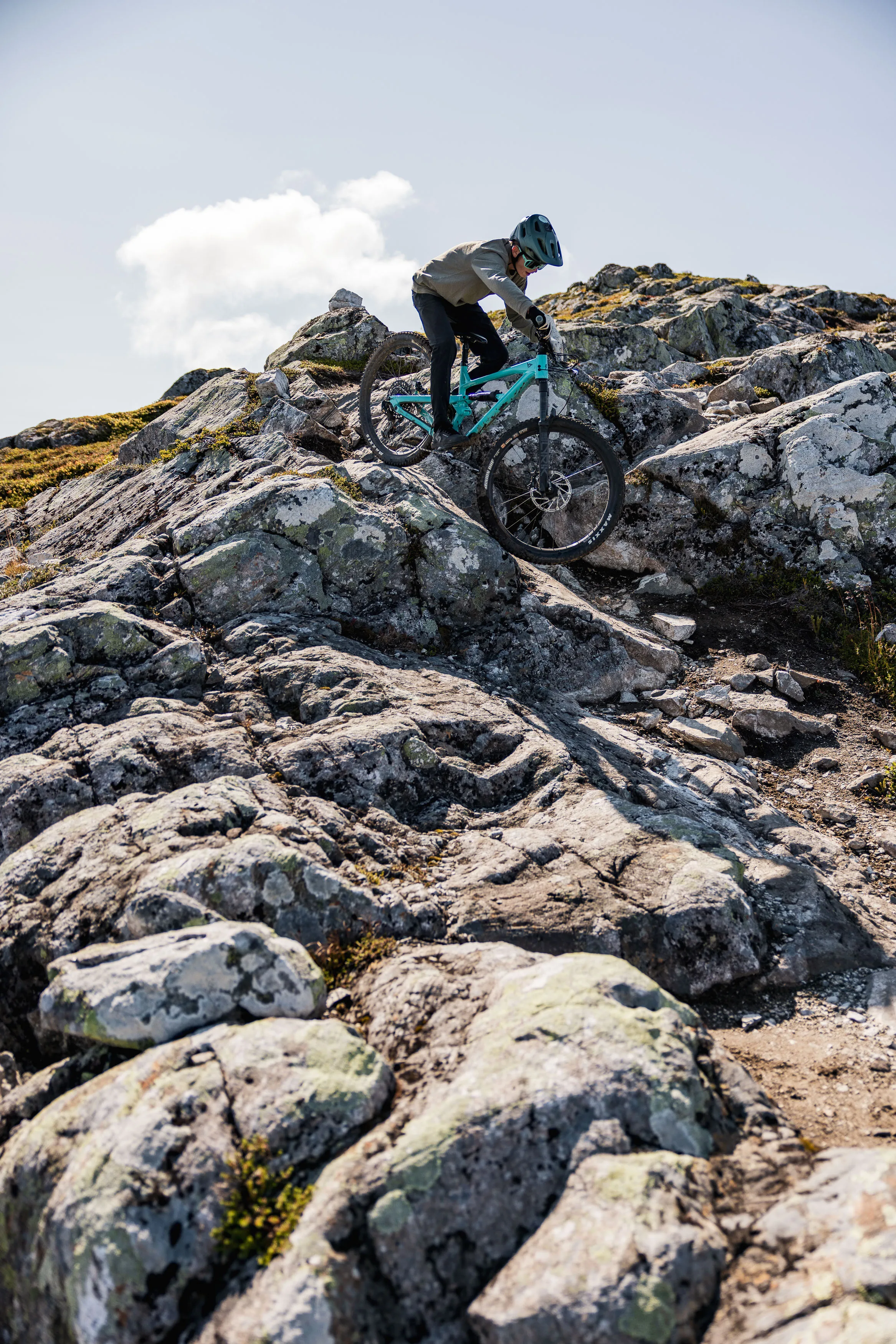 Mountainbiker bewältigt eine steile Passage zwischen großen hellen Felsen