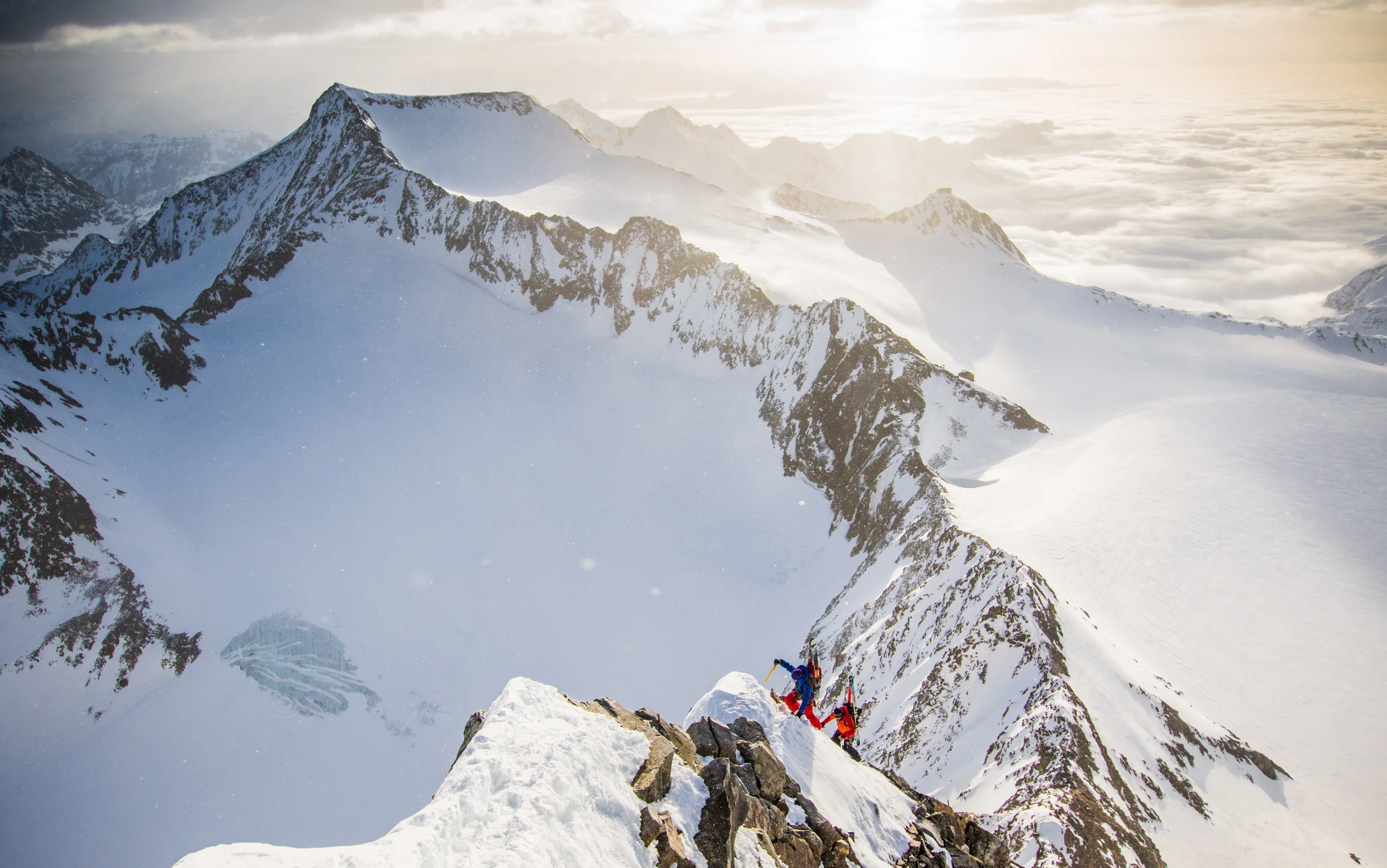 Florian Häusler und Tobias Baur steigen über einen verschneiten Grat über dem Wolkenmeer